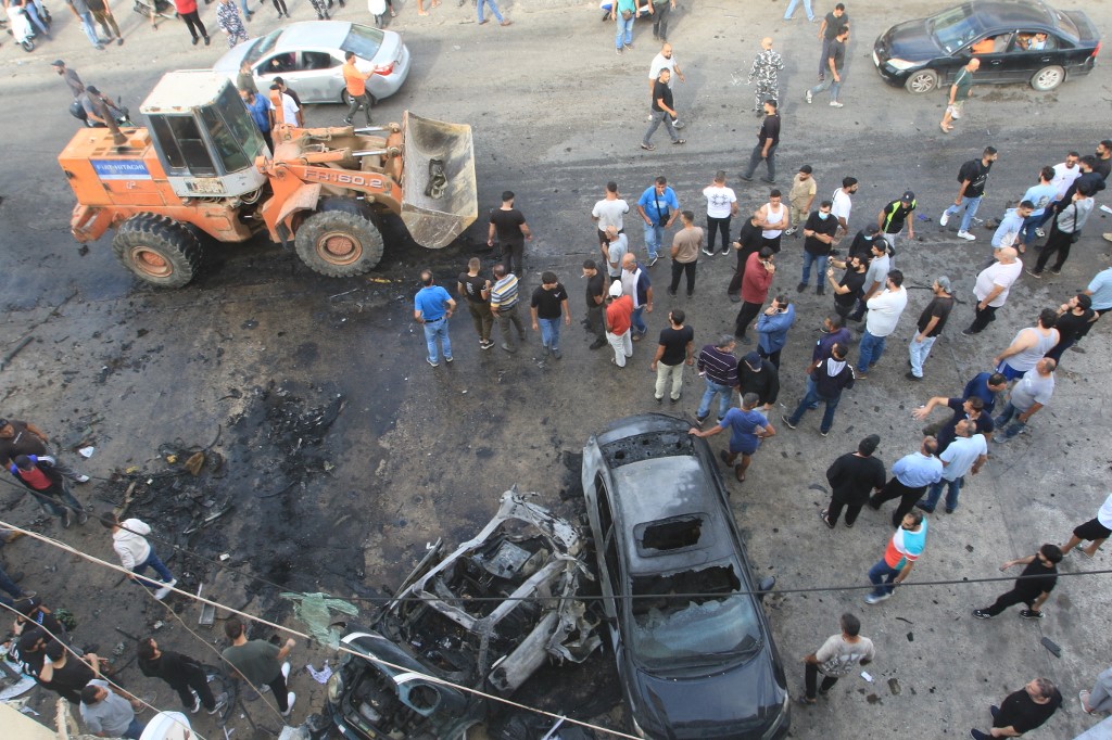 People gather at the site of an Israeli drone attack on a vehicle in the southern Lebanese village of Doueir