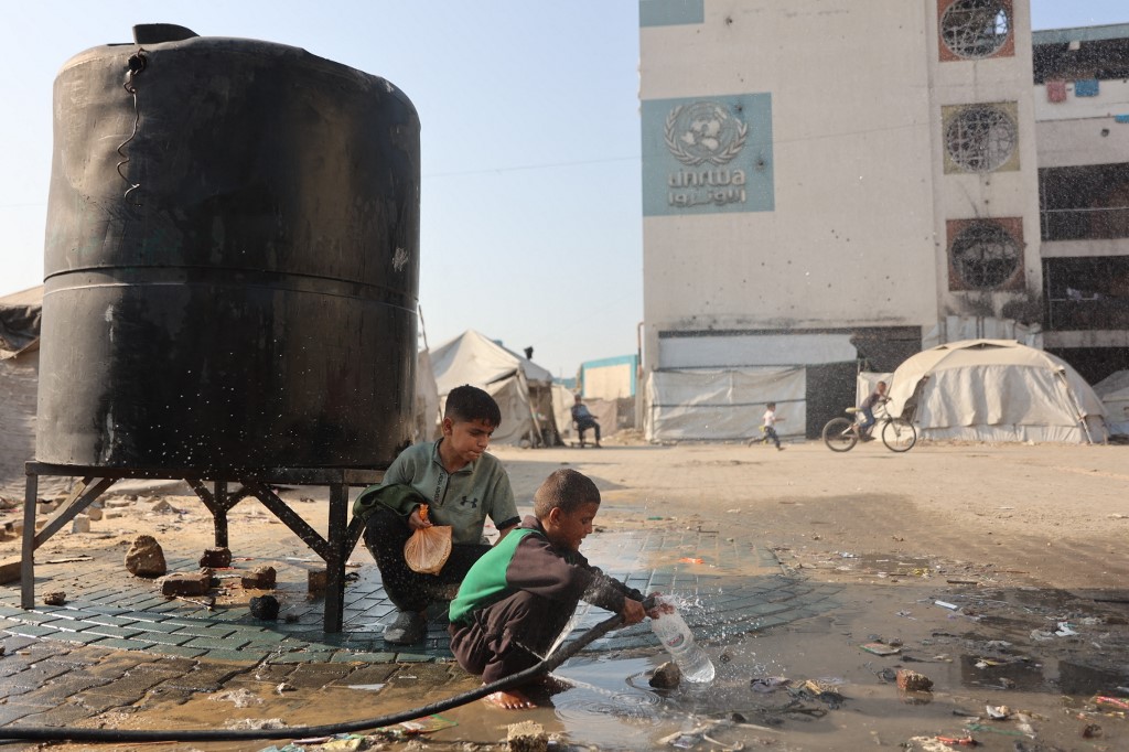 A boy fills a plastic bottle with water inside a camp for displaced Palestinians at a school-turned-shelter in Al-Rimal neighbourhood of Gaza City on November 5, 2025. [File: Omar Al Qattaa]