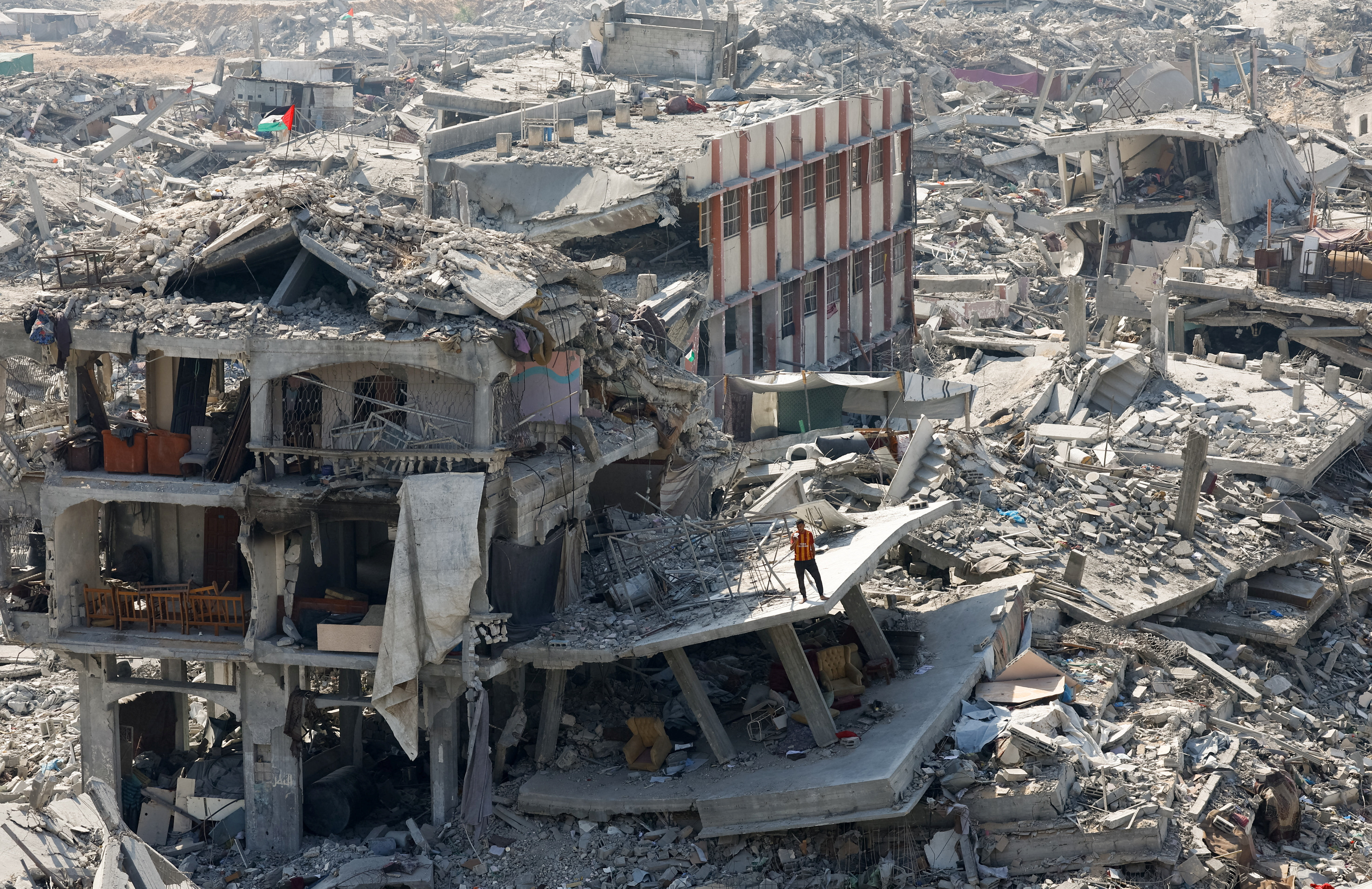 A Palestinian stands next to the rubble of destroyed buildings in Gaza City