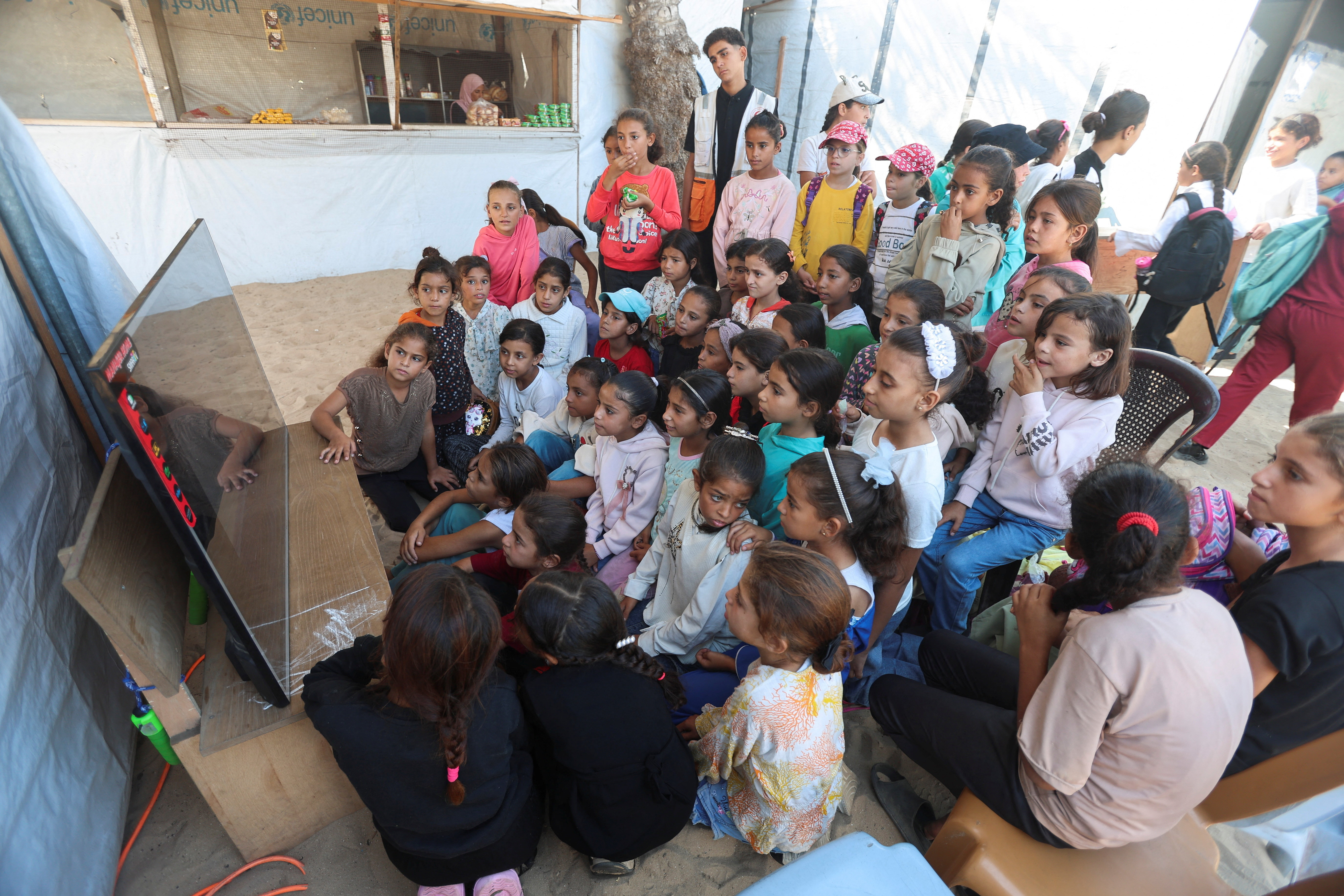 Palestinian children watch cartoons in Khan Younis in the southern Gaza Strip, October 28, 2025. [Ramadan Abed/Reuters]