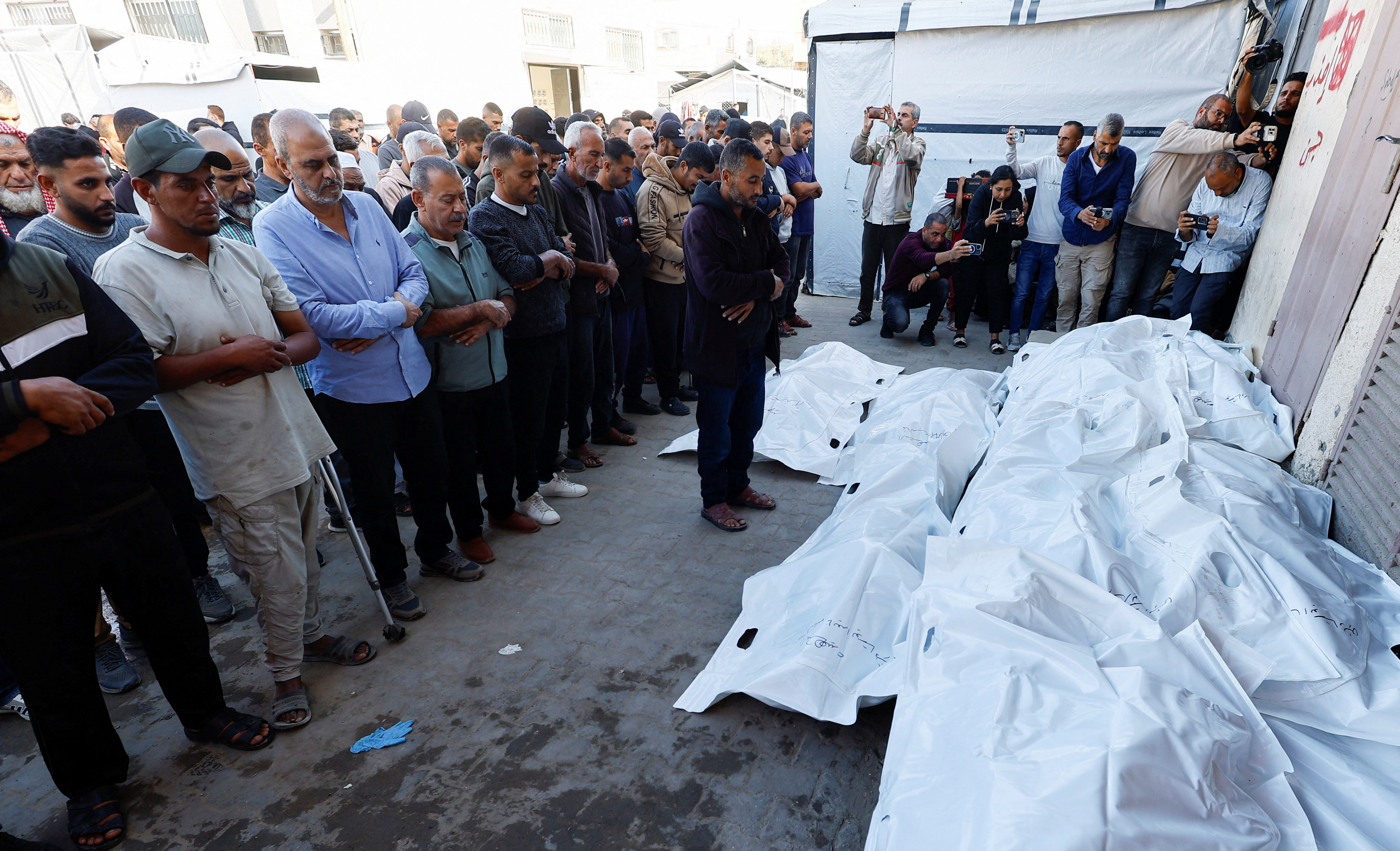 Mourners pray as they attend the funeral of Palestinians who