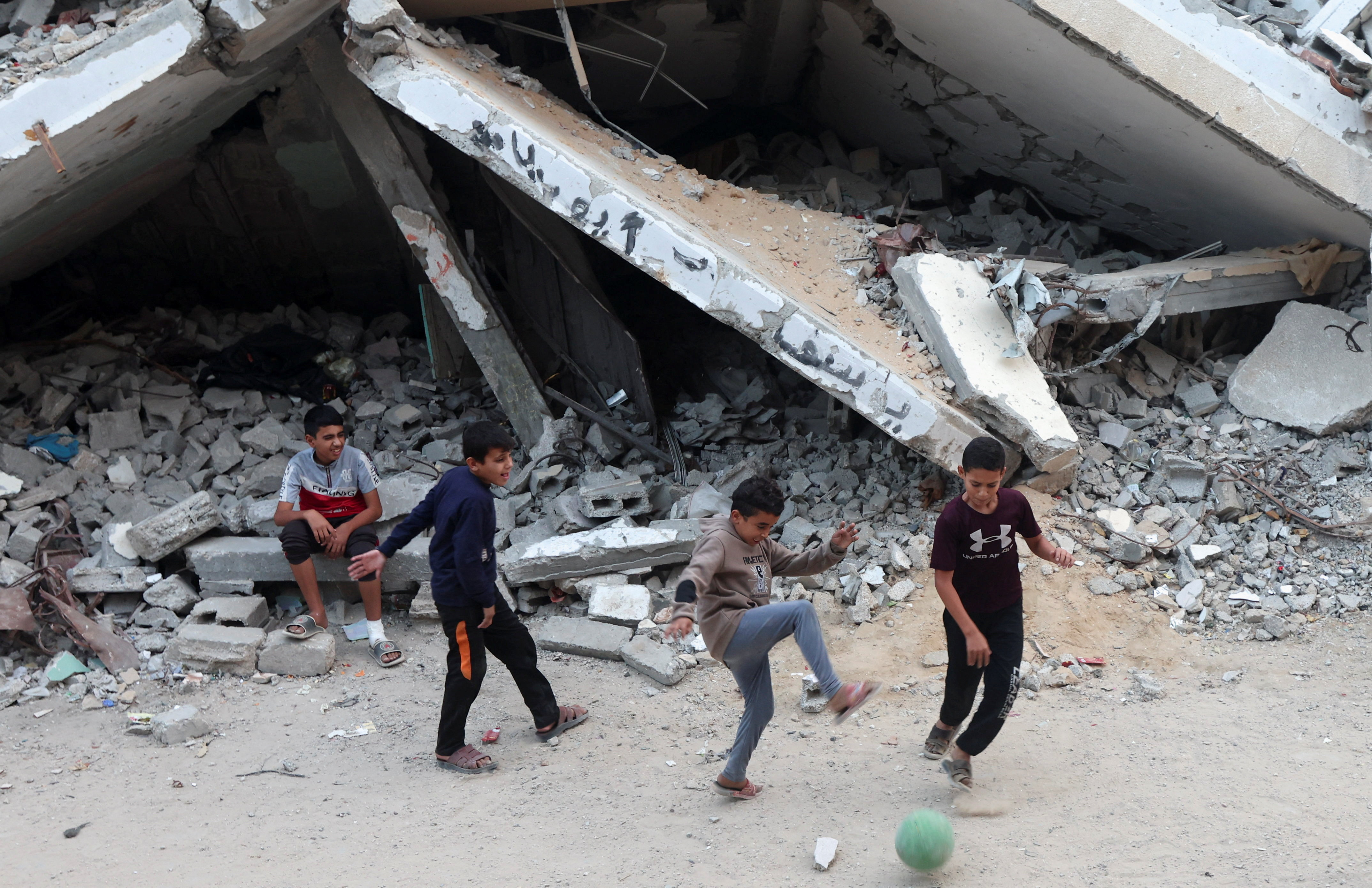 Palestinian children play with a ball among piles of rubble and damaged buildings in Khan Younis in the southern Gaza Strip, November 24, 2025. REUTERS/Ramadan Abed