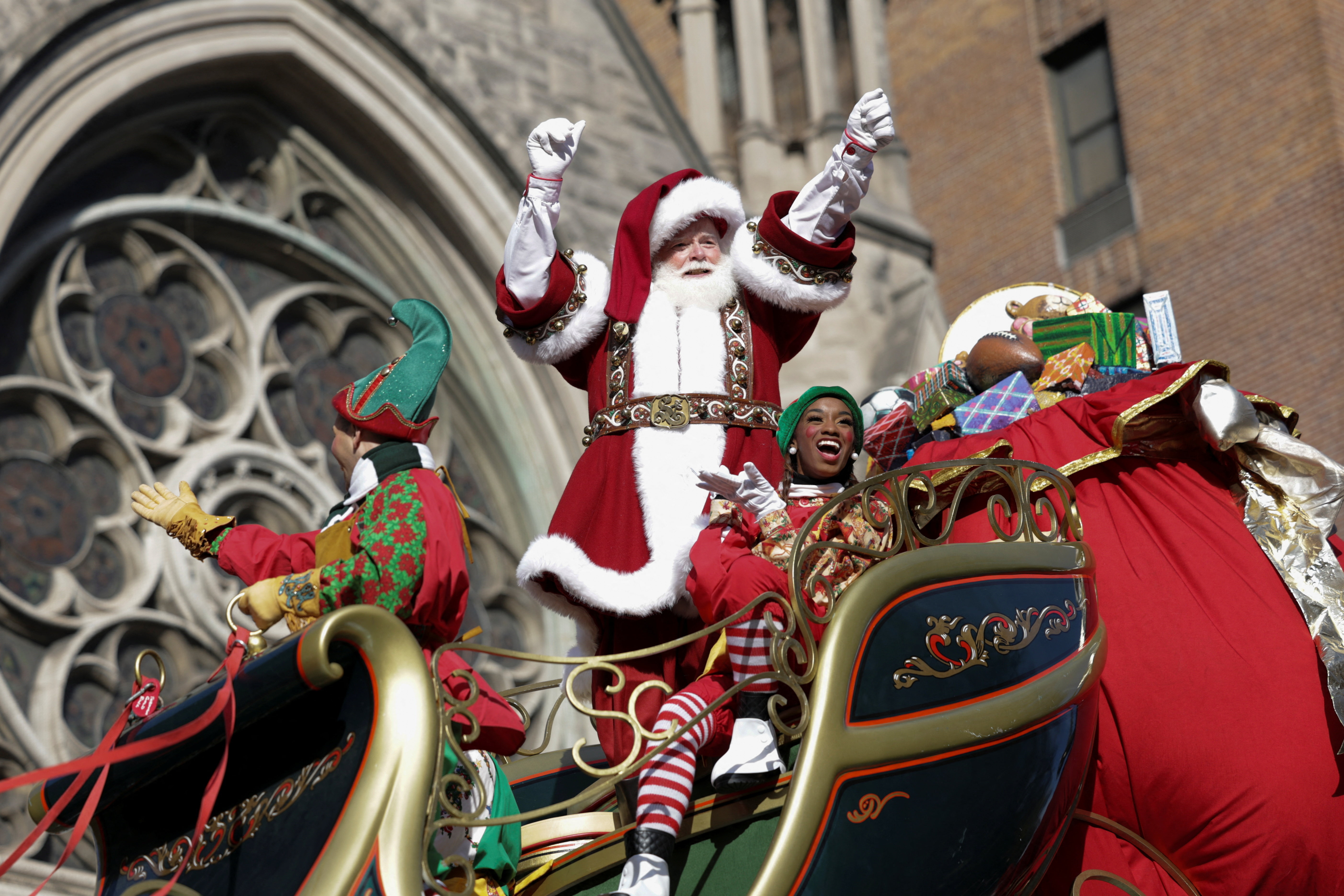 A Santa Claus waves his arms from a sleigh-themed float at the Macy's Thanksgiving Day parade