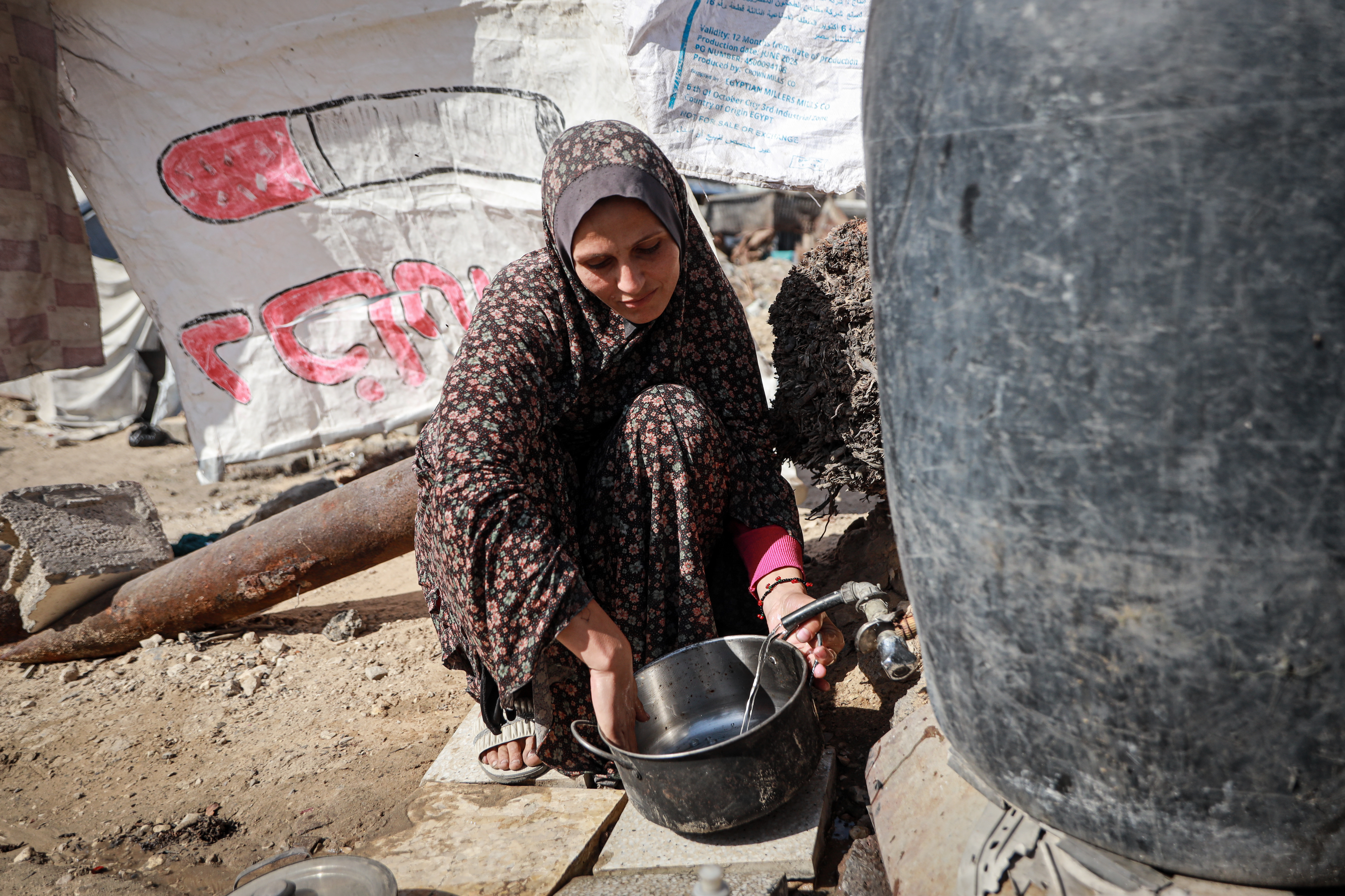 Woman collects water from a tank