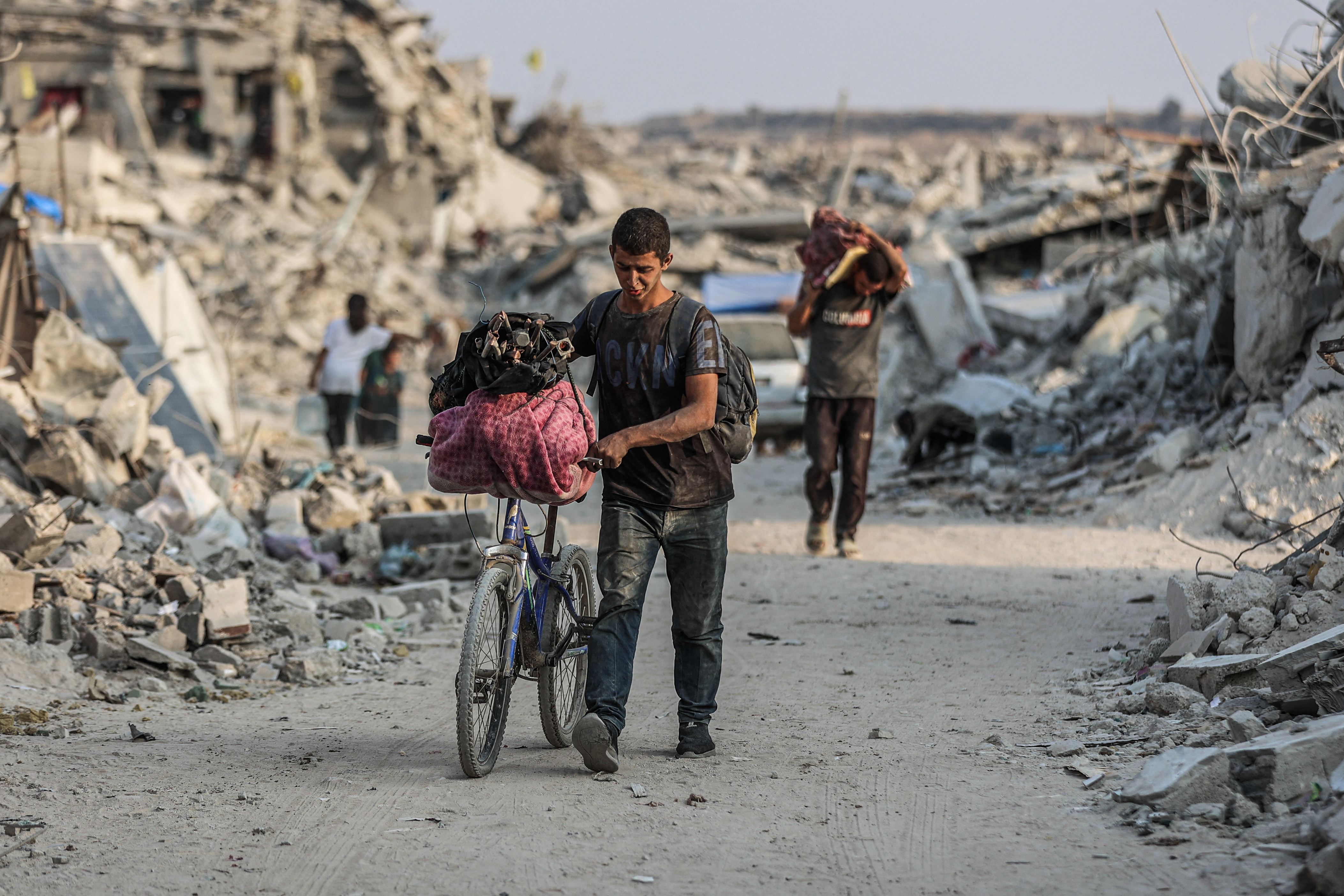 A Palestinian man pushes his bicycle along a road surrounded by the rubble of destroyed buildings in Jabalia, in the northern Gaza Strip, on November 7, 2025.