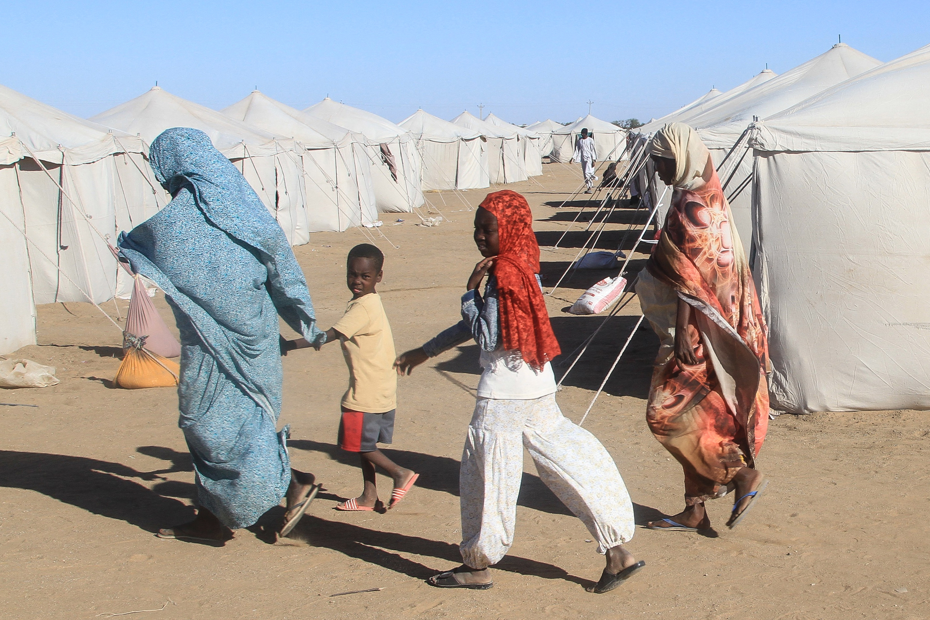 Sudanese who fled El-Fasher walk past tents at the Al-Afad camp for displaced people in the town of Al-Dabba, northern Sudan