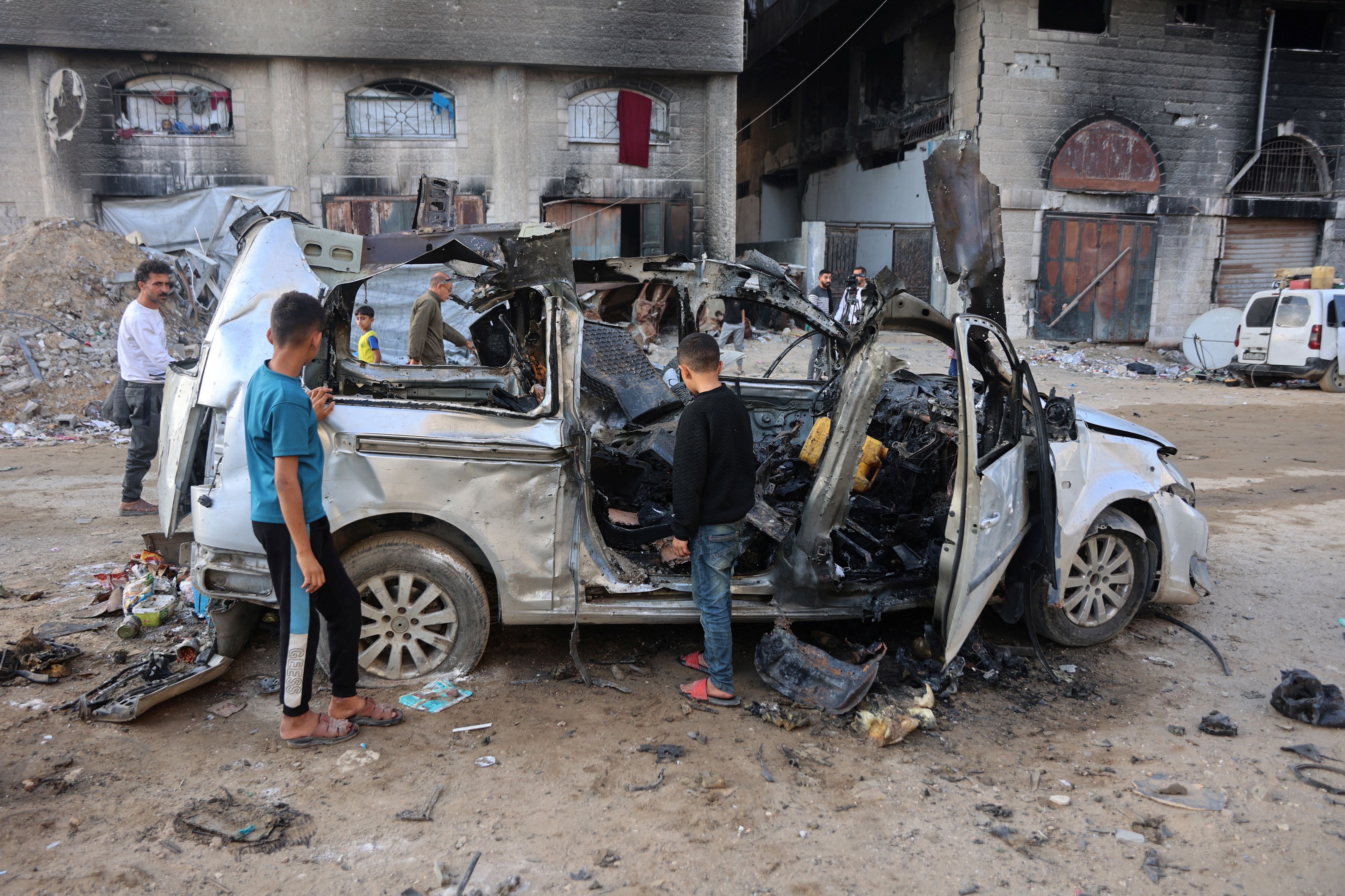 Palestinian boys inspect what remains of a destroyed vehicle
