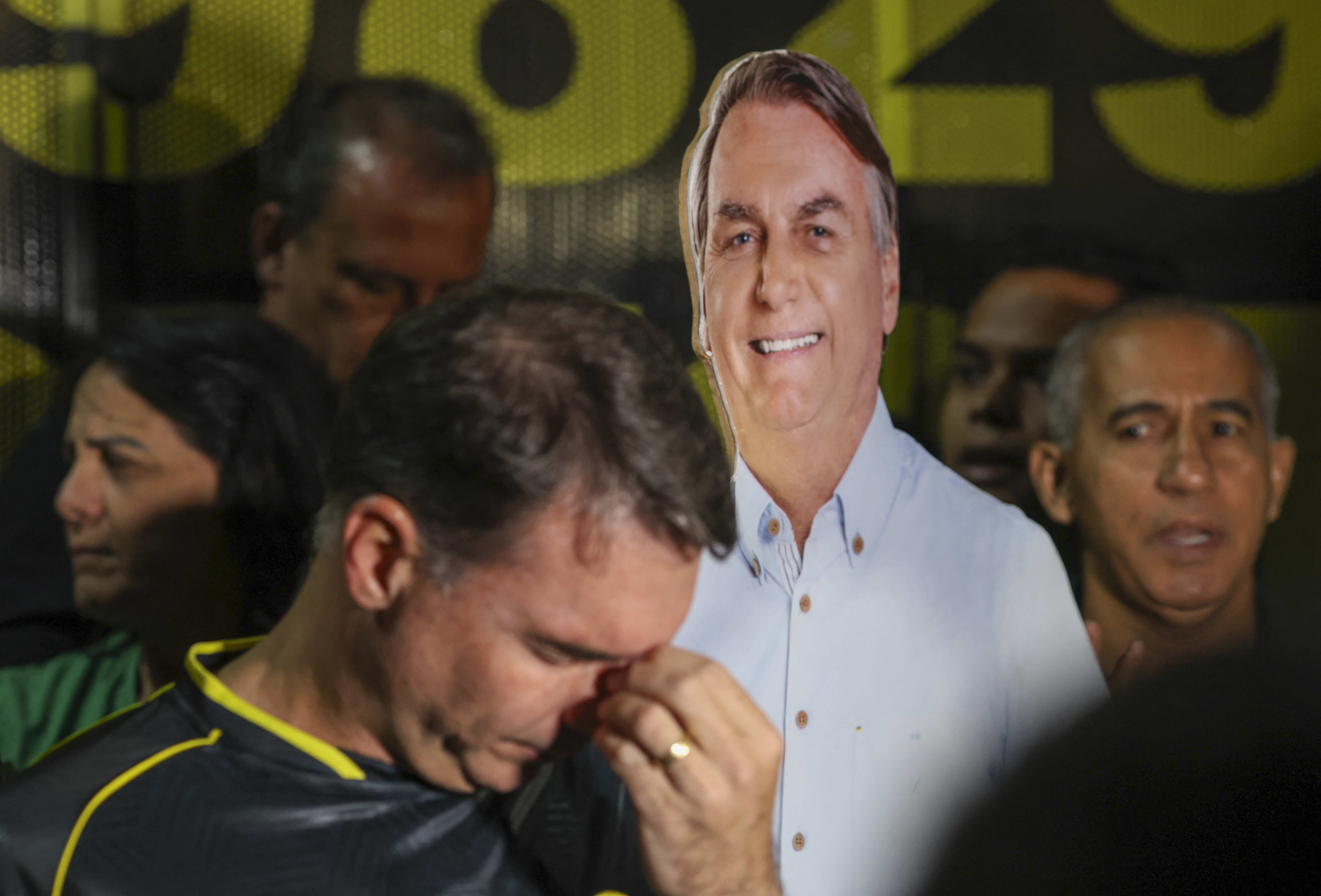 Brazilian Senator Flavio Bolsonaro attends a vigil for his imprisoned father, former President Jair Bolsonaro (represented in the cardboard cutout), in Brasilia on November 22, 2025 [Sergio Lima/AFP]