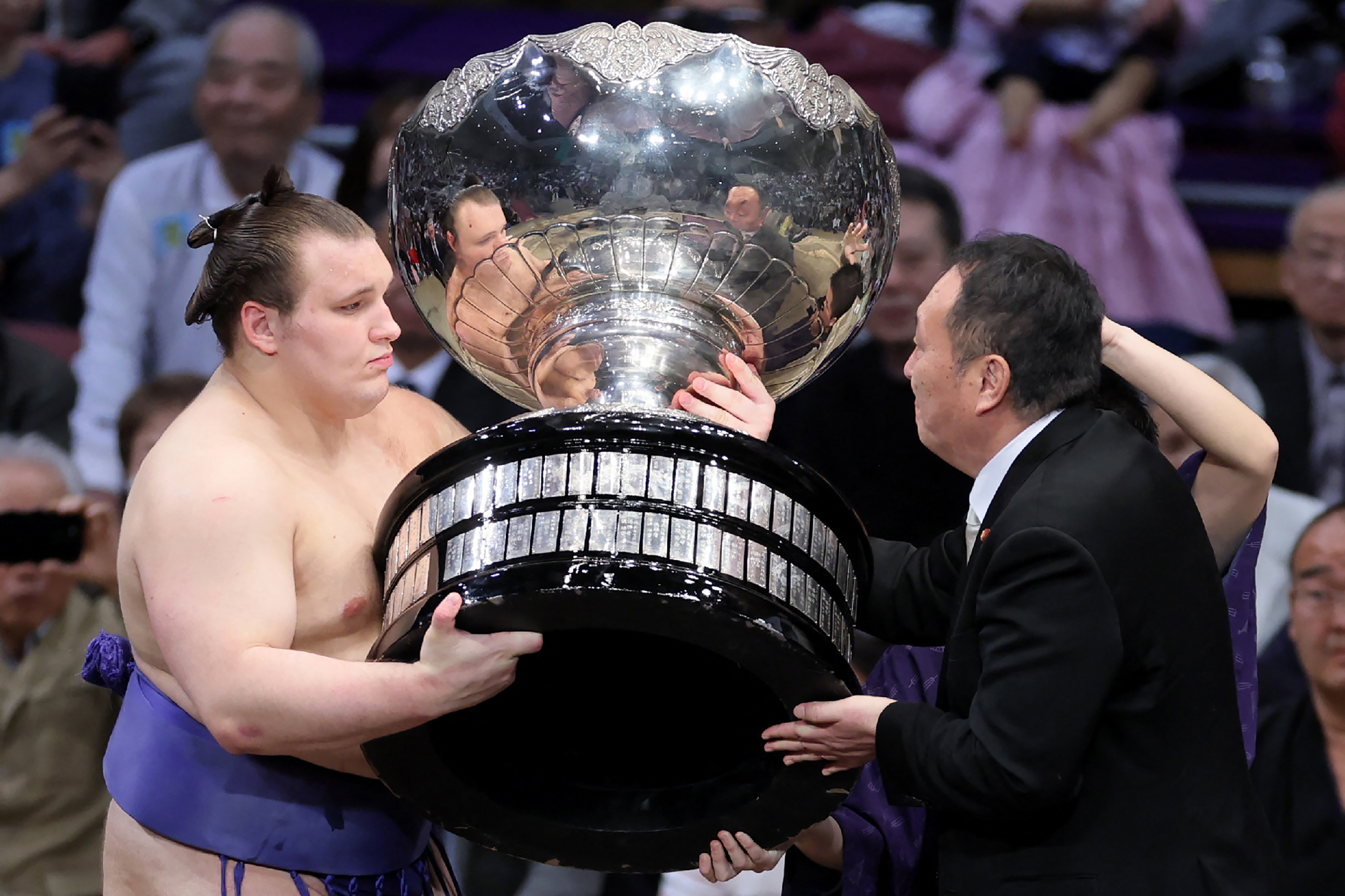Danylo Yavhusishyn, also known by his Japanese ring name Aonishiki Arata (L), receives the Prime Minister's Cup trophy.