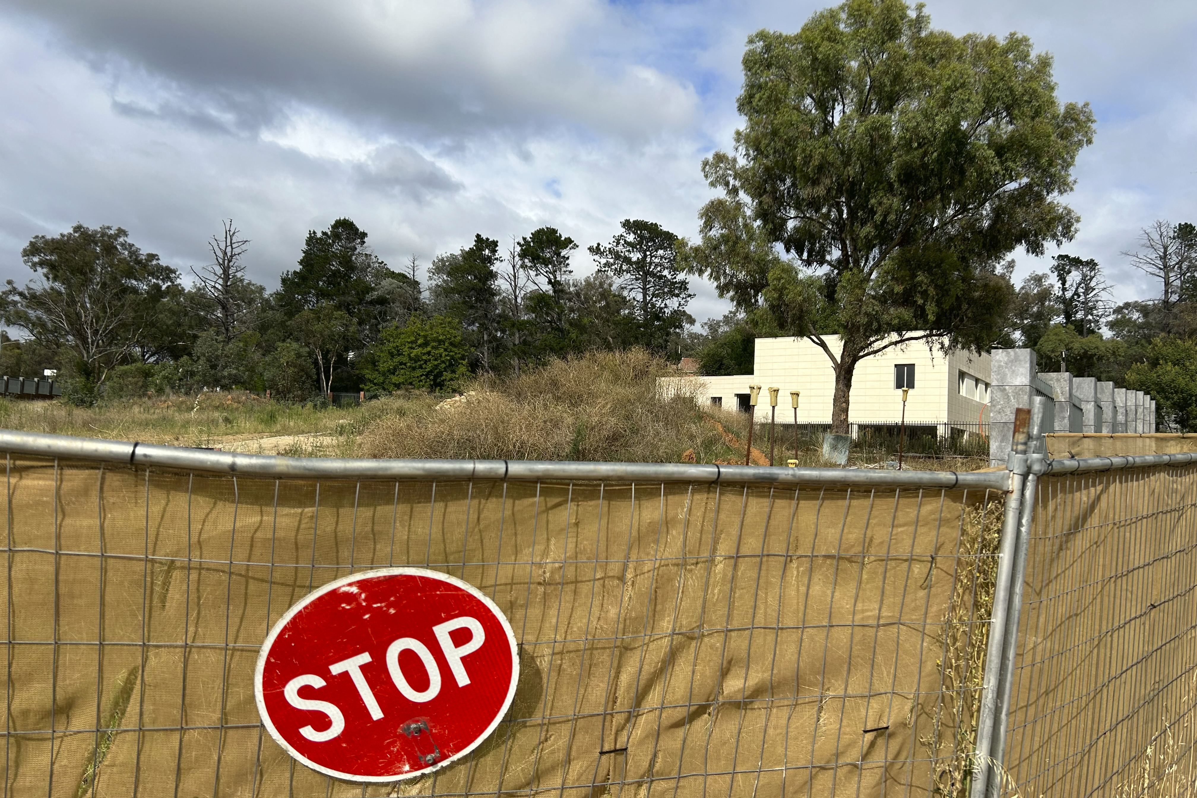 THIS CORRECTS THE PHOTOGRAPHER'S NAME TO MCGUIRK - A sign hangs from a fence surrounding an unoccupied building on the grounds of a proposed new Russian embassy near the Australian Parliament in Canberra, Feb. 28, 2023. Australia's House of Representatives passed legislation Thursday, June 15, 2023, to prevent Russia from building a new embassy near Parliament House on security grounds. (AP Photo/Rod McGuirk)