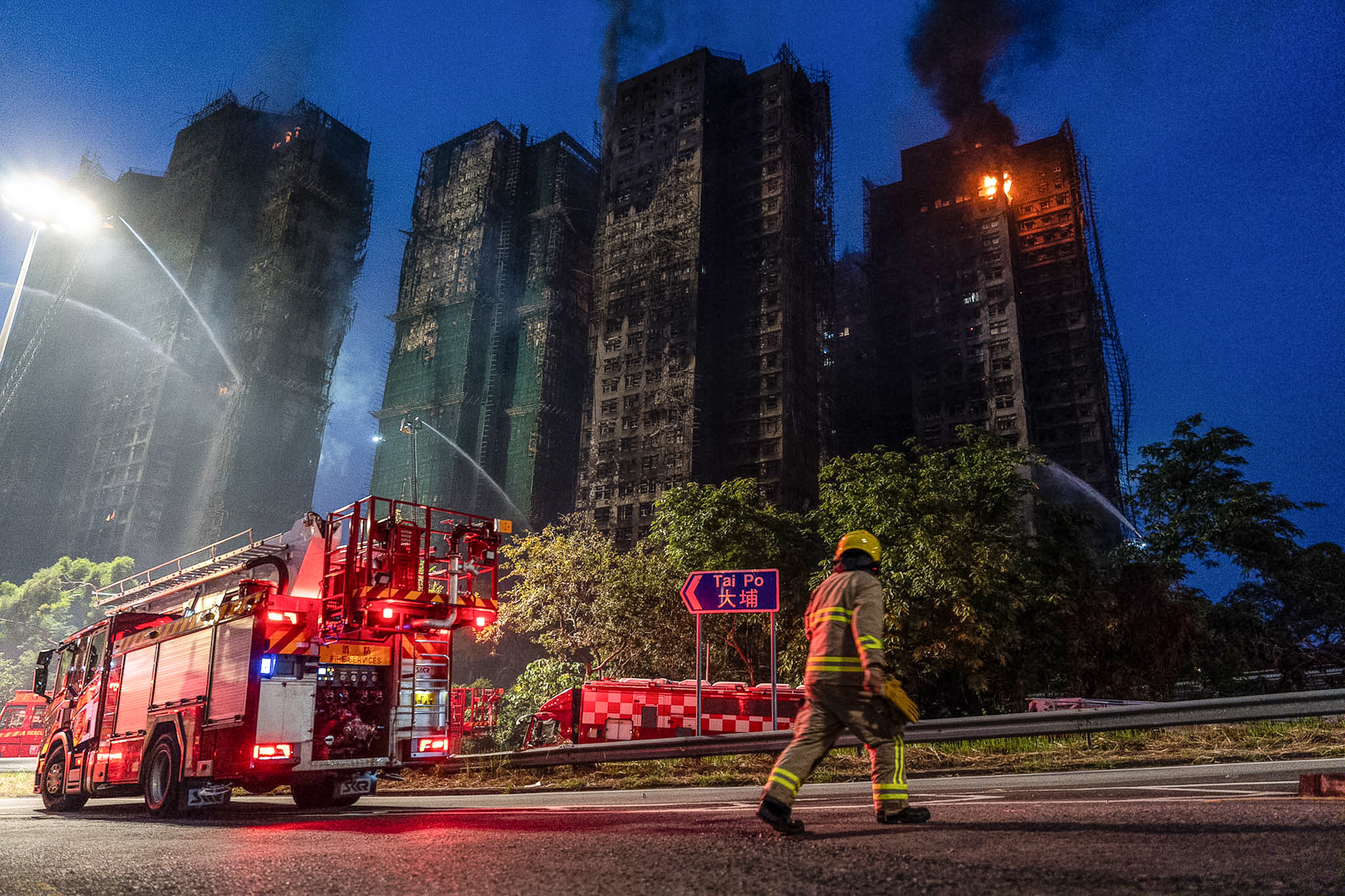 A firefighter walks past the fire scene at Wang Fuk Court [Chan Long Hei/AP Photo]