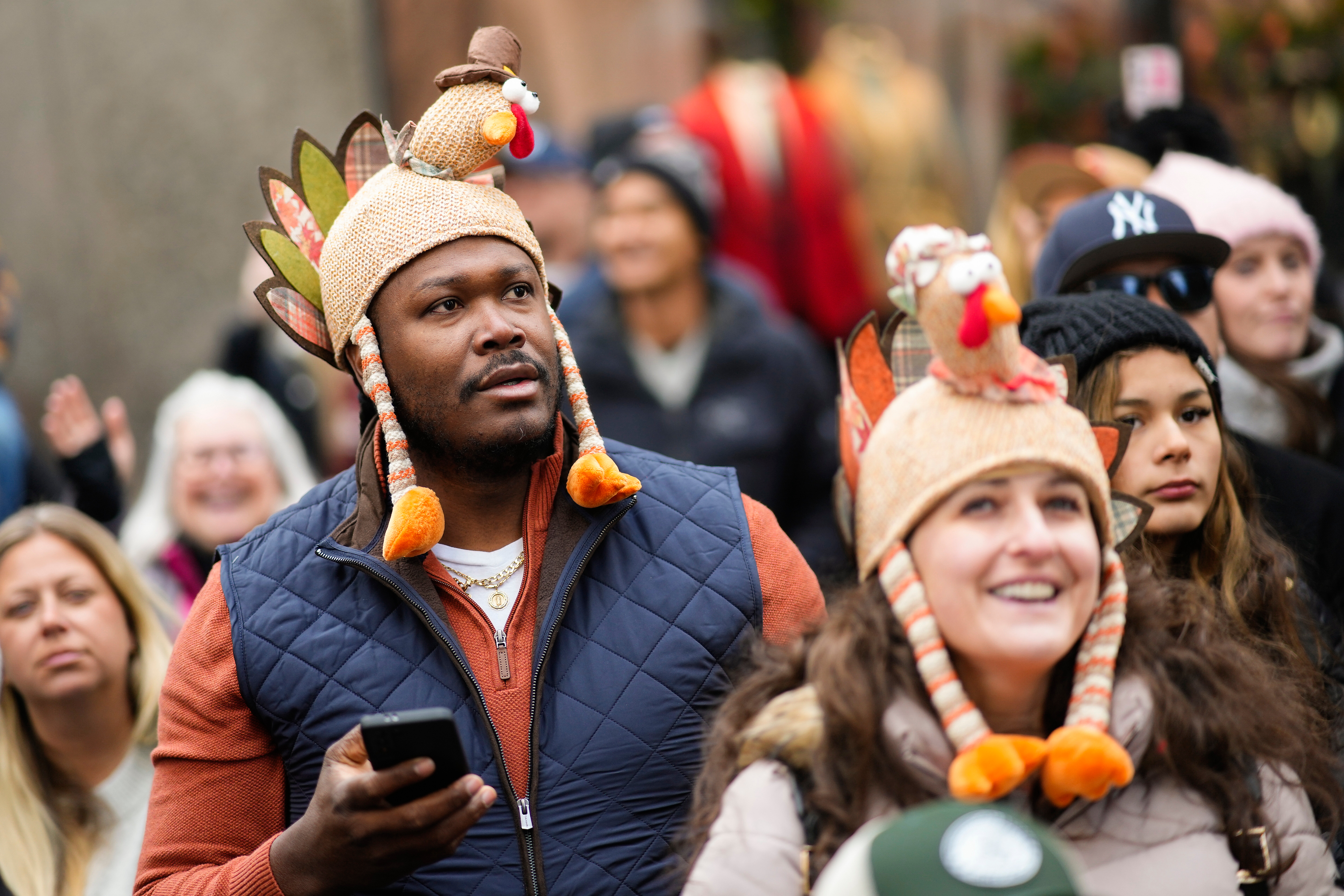 People wearing turkey-themed hats watch the Macy's Thanksgiving Day parade