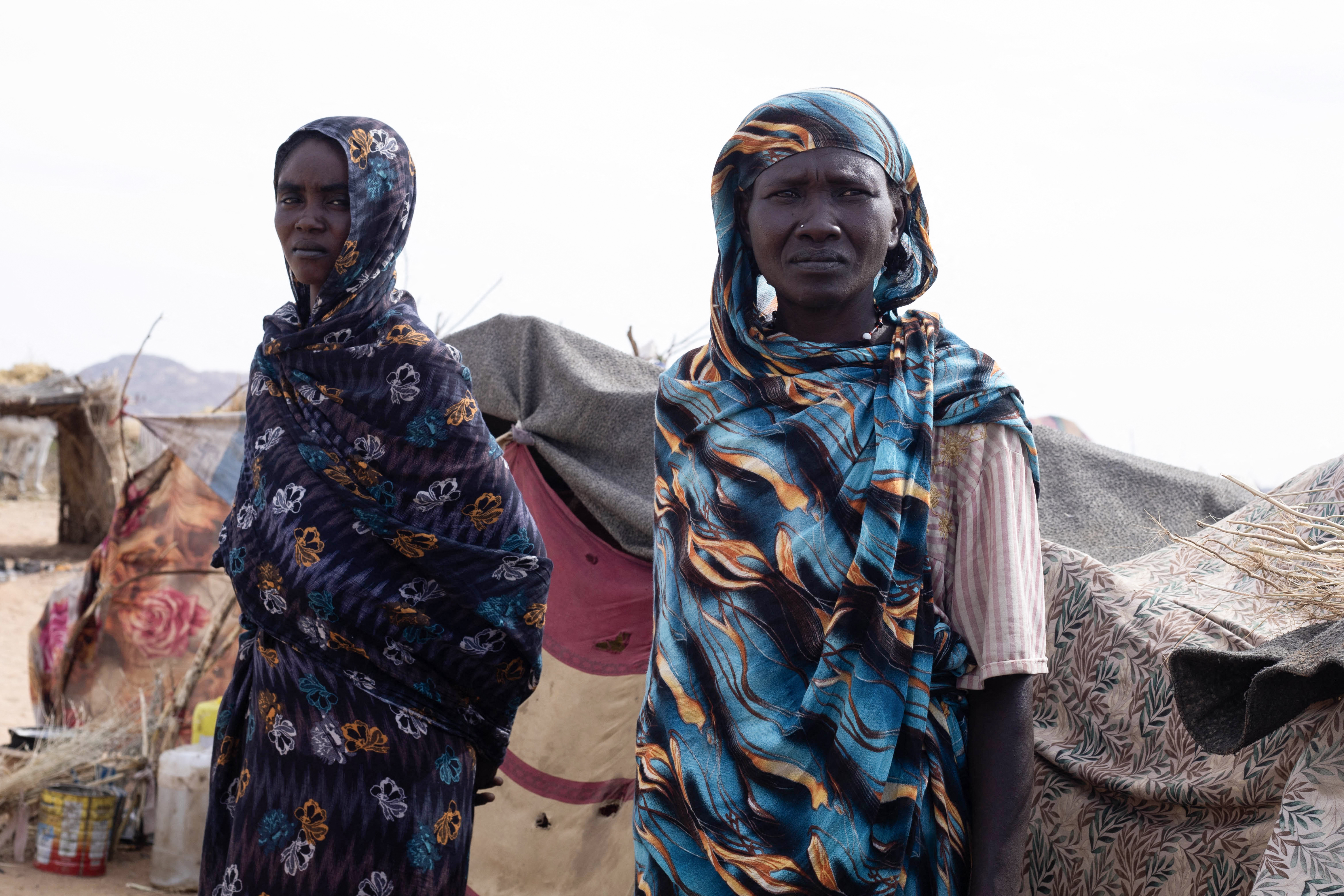 Displaced Sudanese women who fled El-Fasher after the city fell to the Rapid Support Forces (RSF), stand in front of their makeshift shelter in the Um Yanqur camp, located on the southwestern edge of Tawila, in war-torn Sudan's western Darfur region on November 3, 2025.