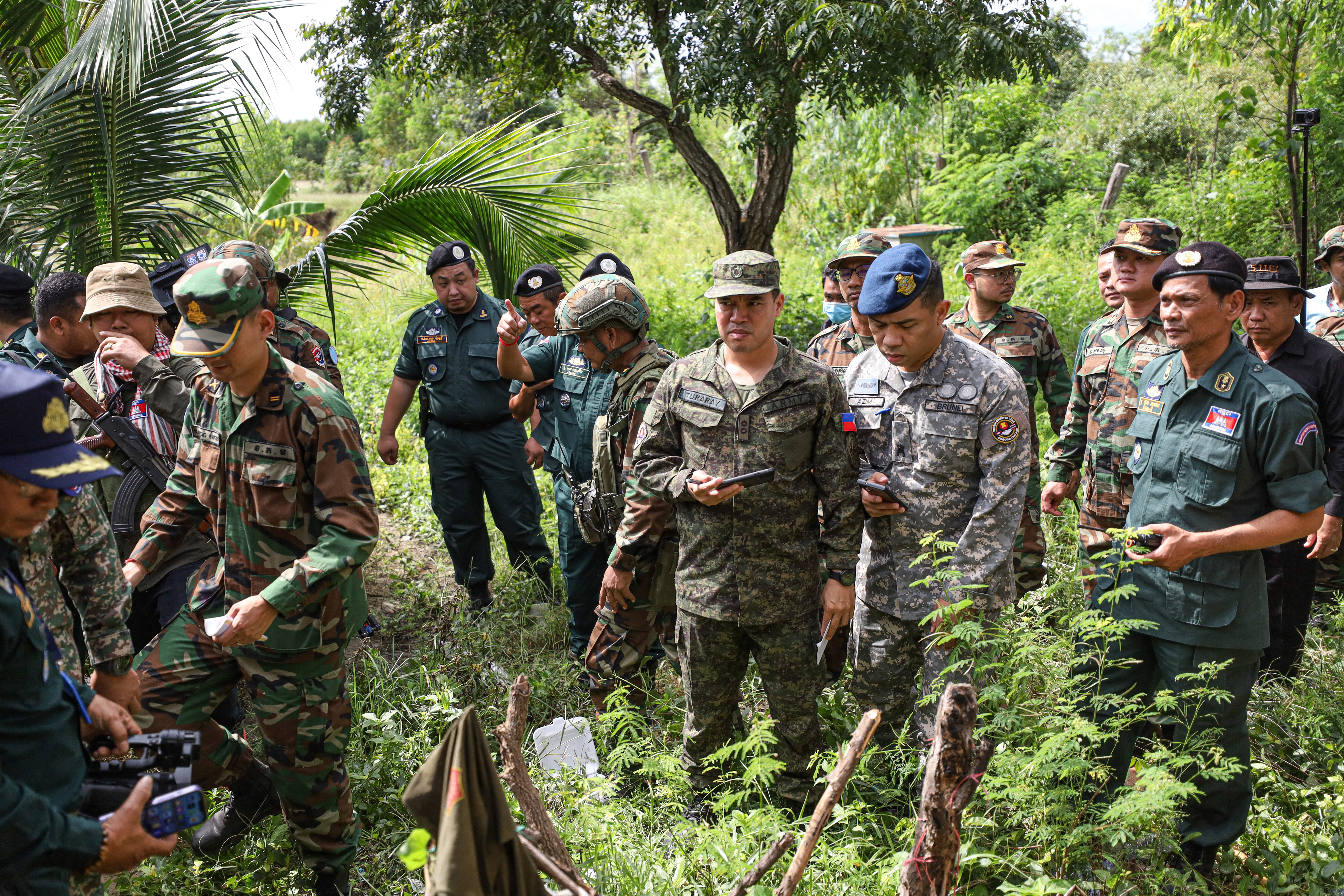 This handout photo taken and released by Agence Kampuchea Press (AKP) on November 13, 2025 shows a delegation from the ASEAN Observer Team (AOT) visiting an area where a civilian was killed a day before along the Cambodia-Thailand border in Banteay Meanchey province, as both sides traded accusations of fresh clashes along their shared frontier.