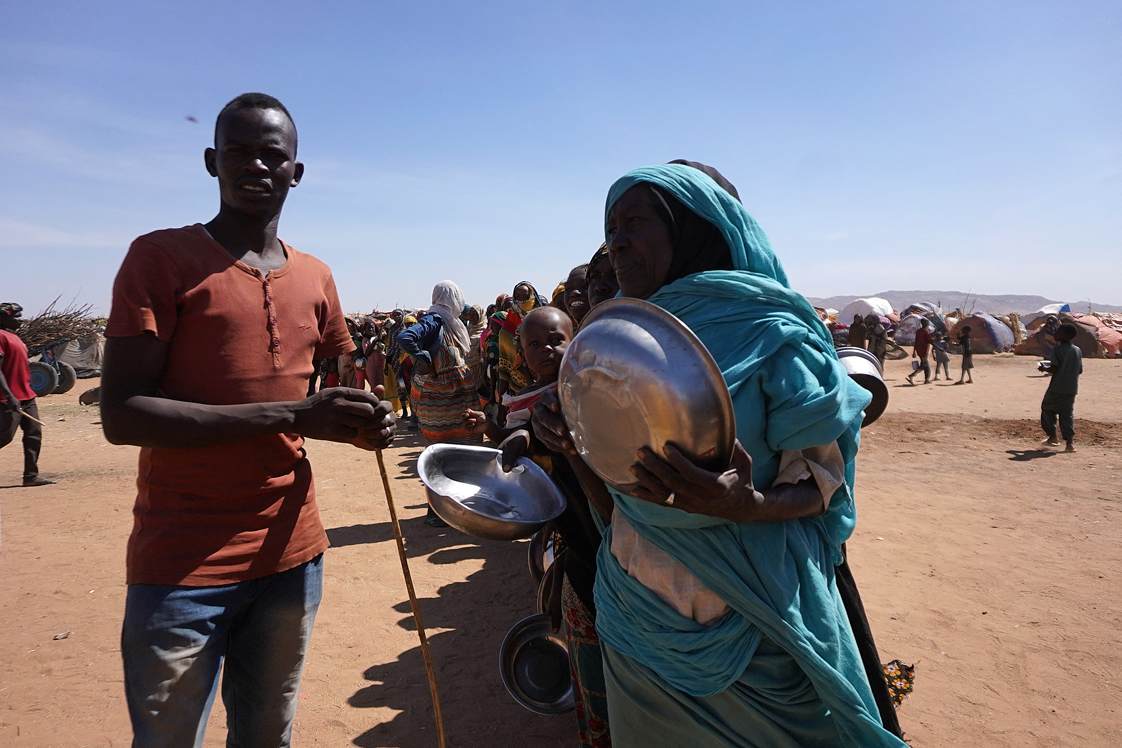 A handout picture released by the International Committee of the Red Cross (ICRC) on November 18, 2025 shows displaced civilians who have fled violence in El-Fasher gathering by makeshift camps in the city of Tawila.
