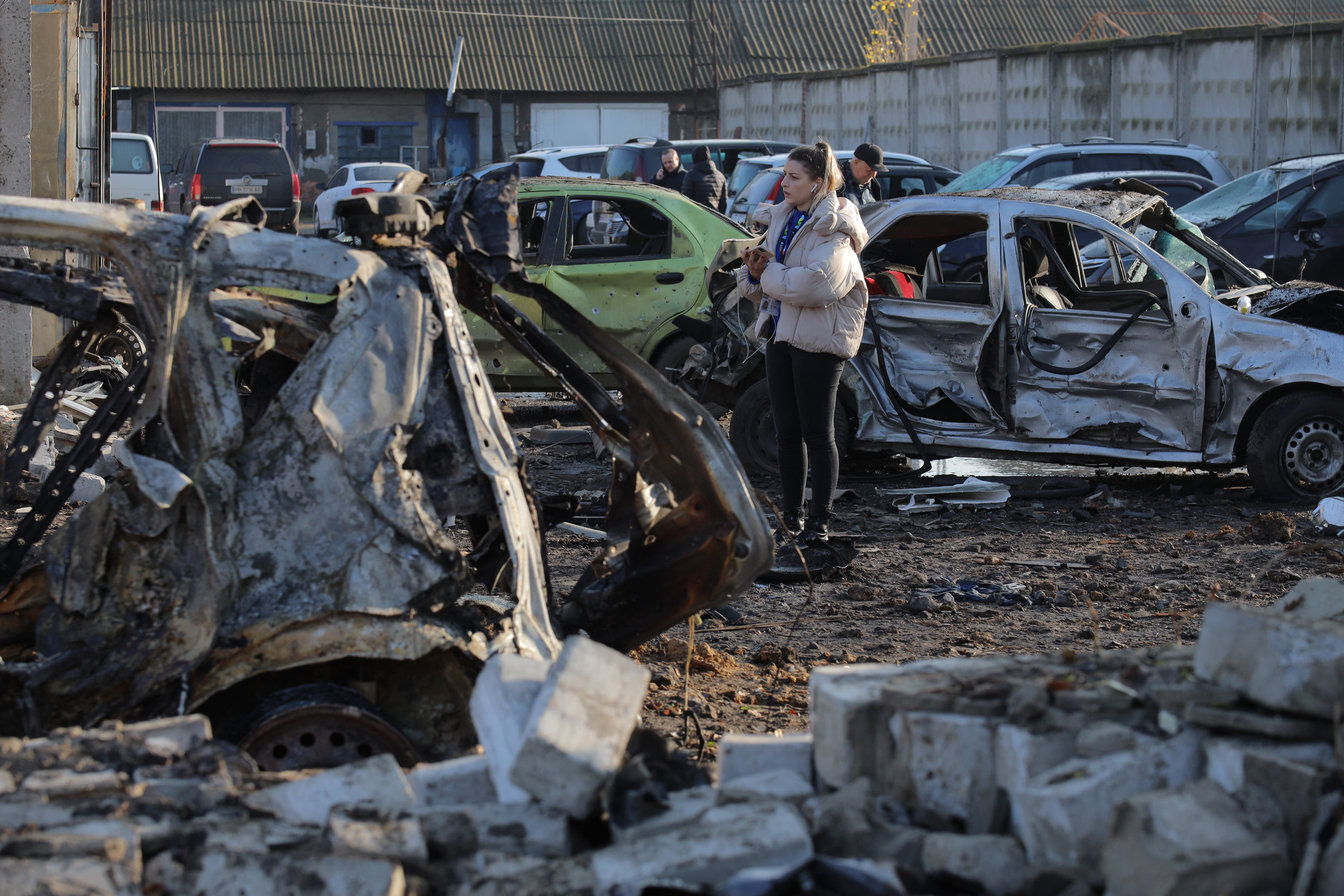 People inspect destroyed cars in the parking lot of a car service station following an air attack in Odesa on November 21, 2025, amid the Russian invasion in Ukraine.