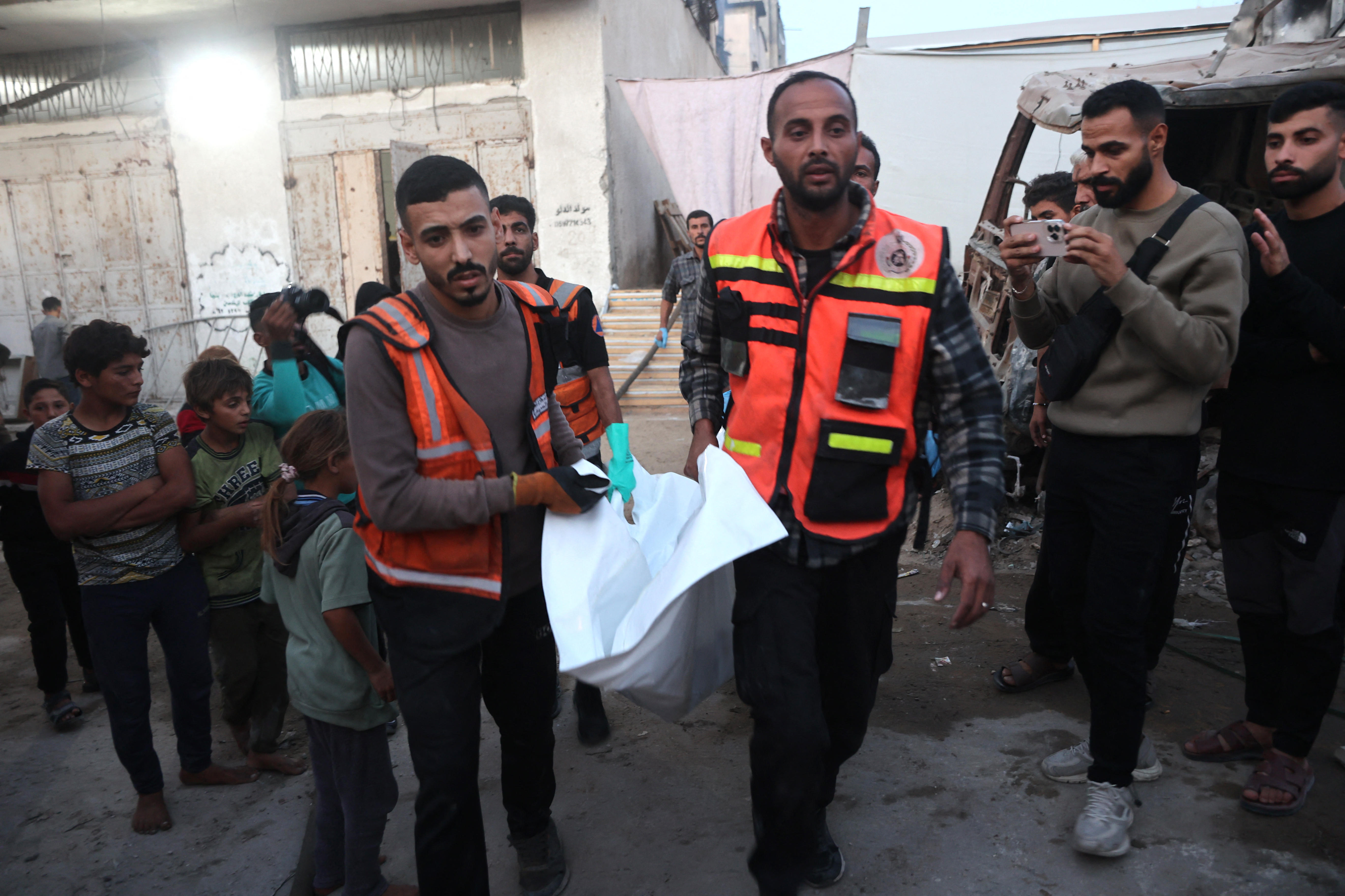 Civil defence personnel carry away a body bag after searching a house targeted in an Israeli airstrikes in Gaza City, on November 22, 2025.