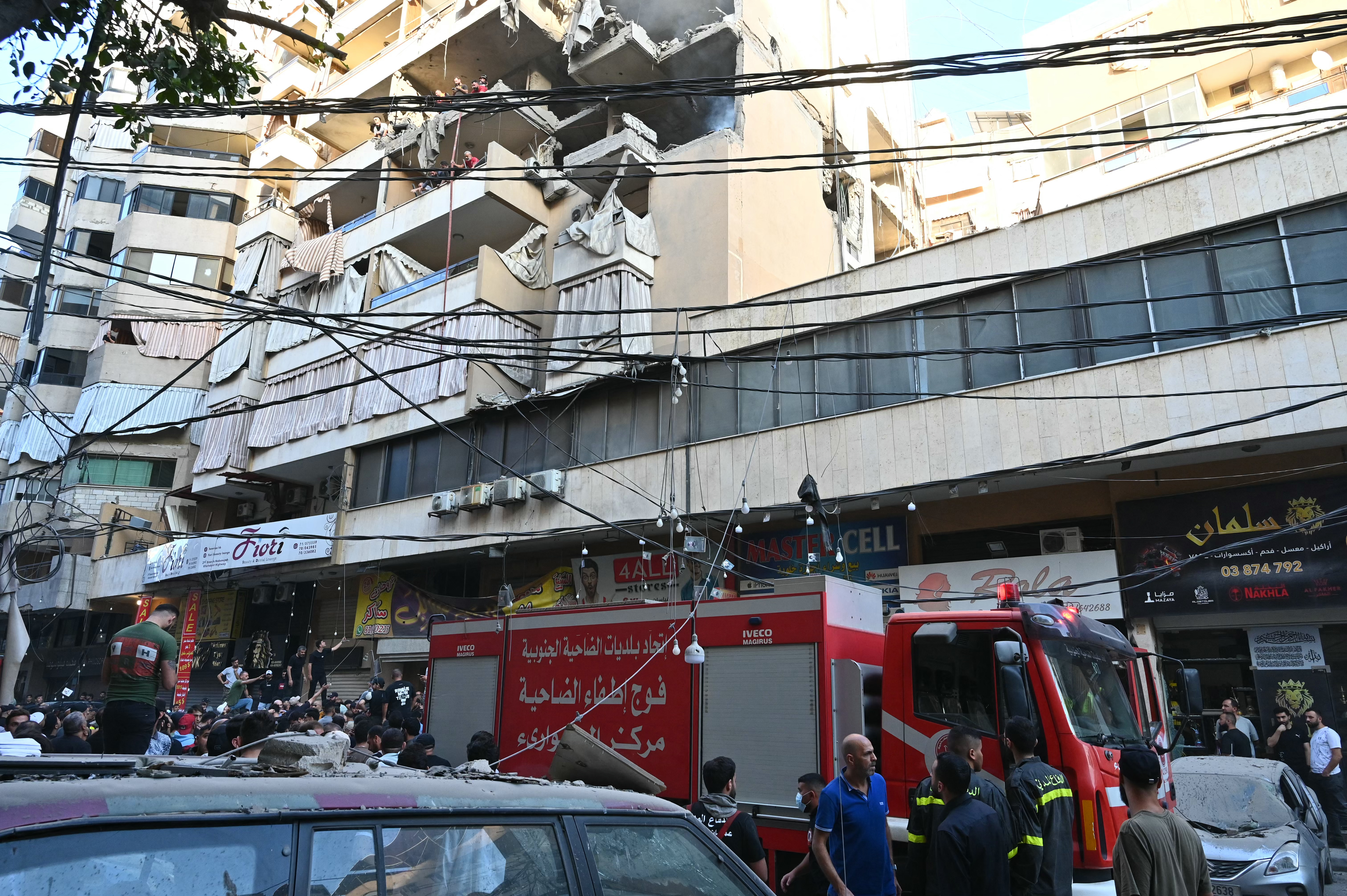 People gather looking at a residential building following an Israeli military strike in the Haret Hreik neighbourhood, of Beirut's southern suburbs on November 23, 2025.