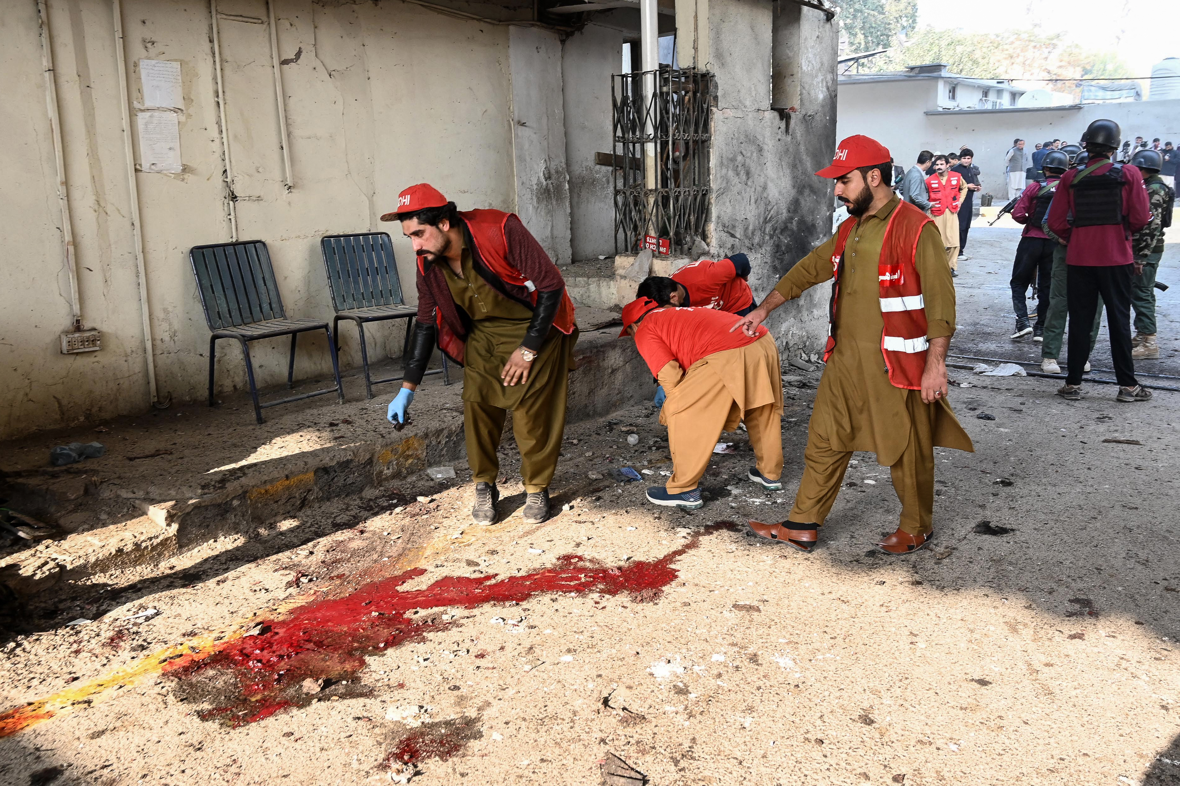 Rescue personnel examine the site of a suicide attack outside the border force headquarters in Peshawar on November 24, 2025.