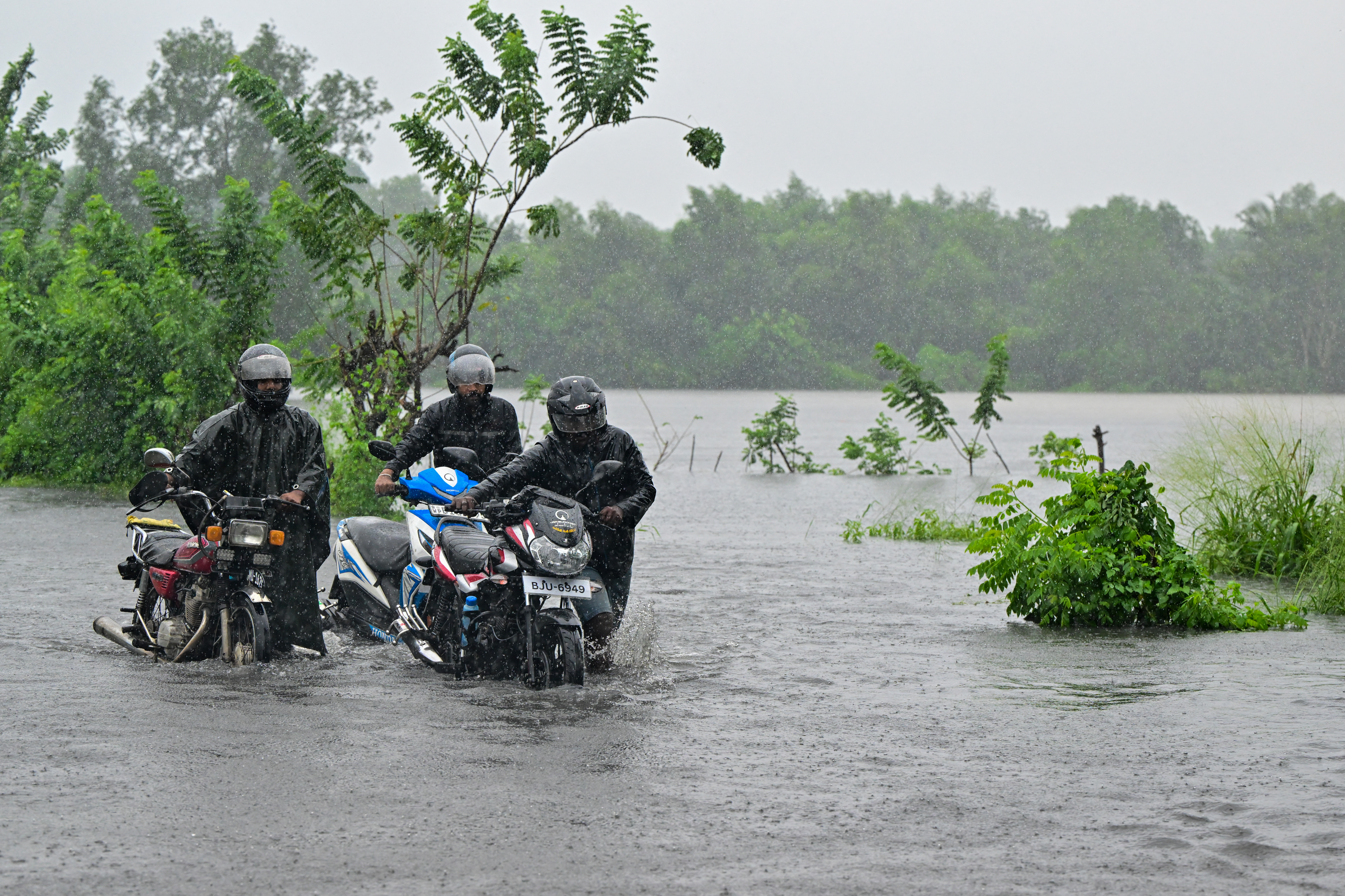 Residents with motorbikes wade through a flooded street after heavy rains.