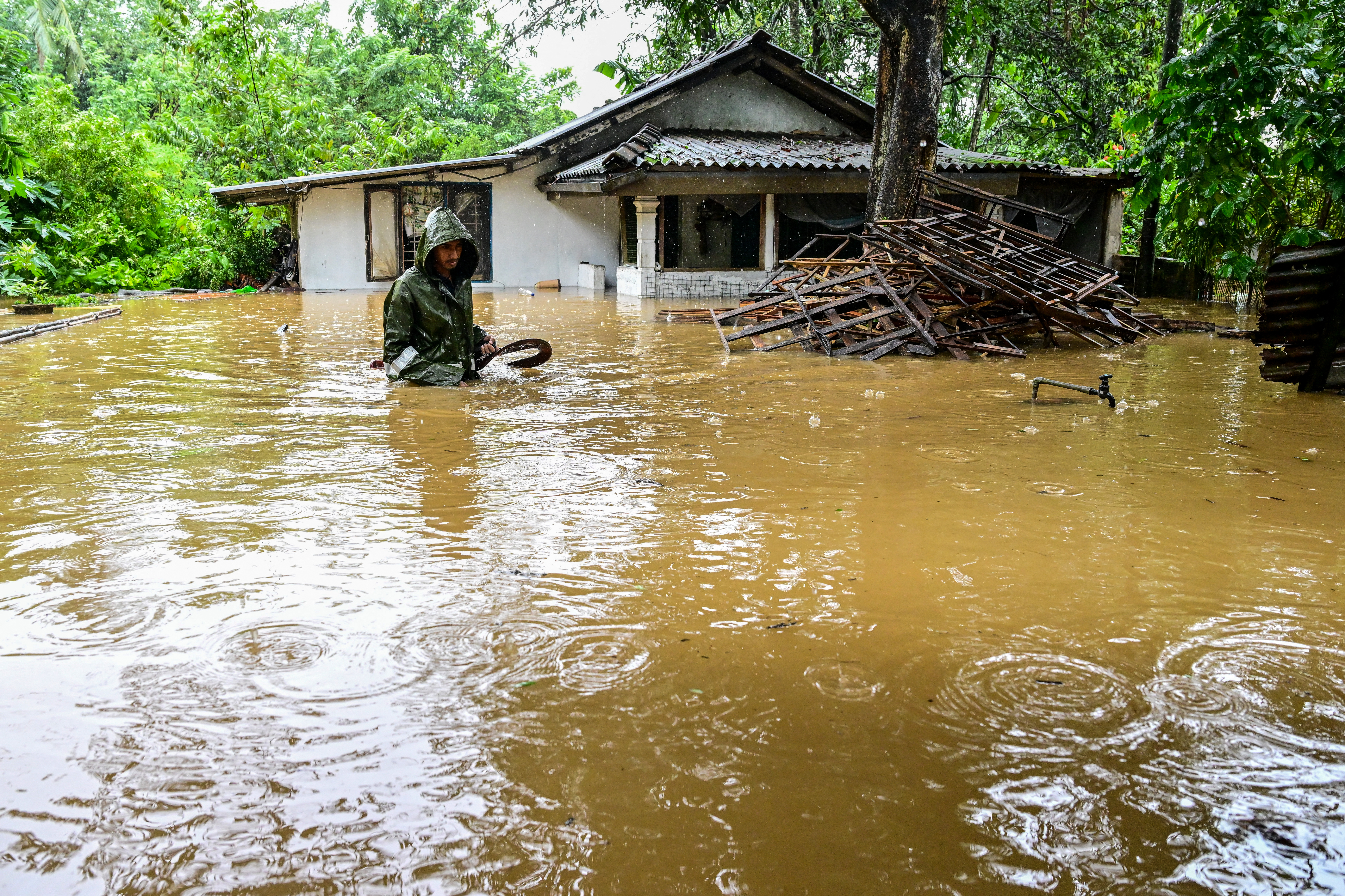 A man wades through floodwaters outside his house.