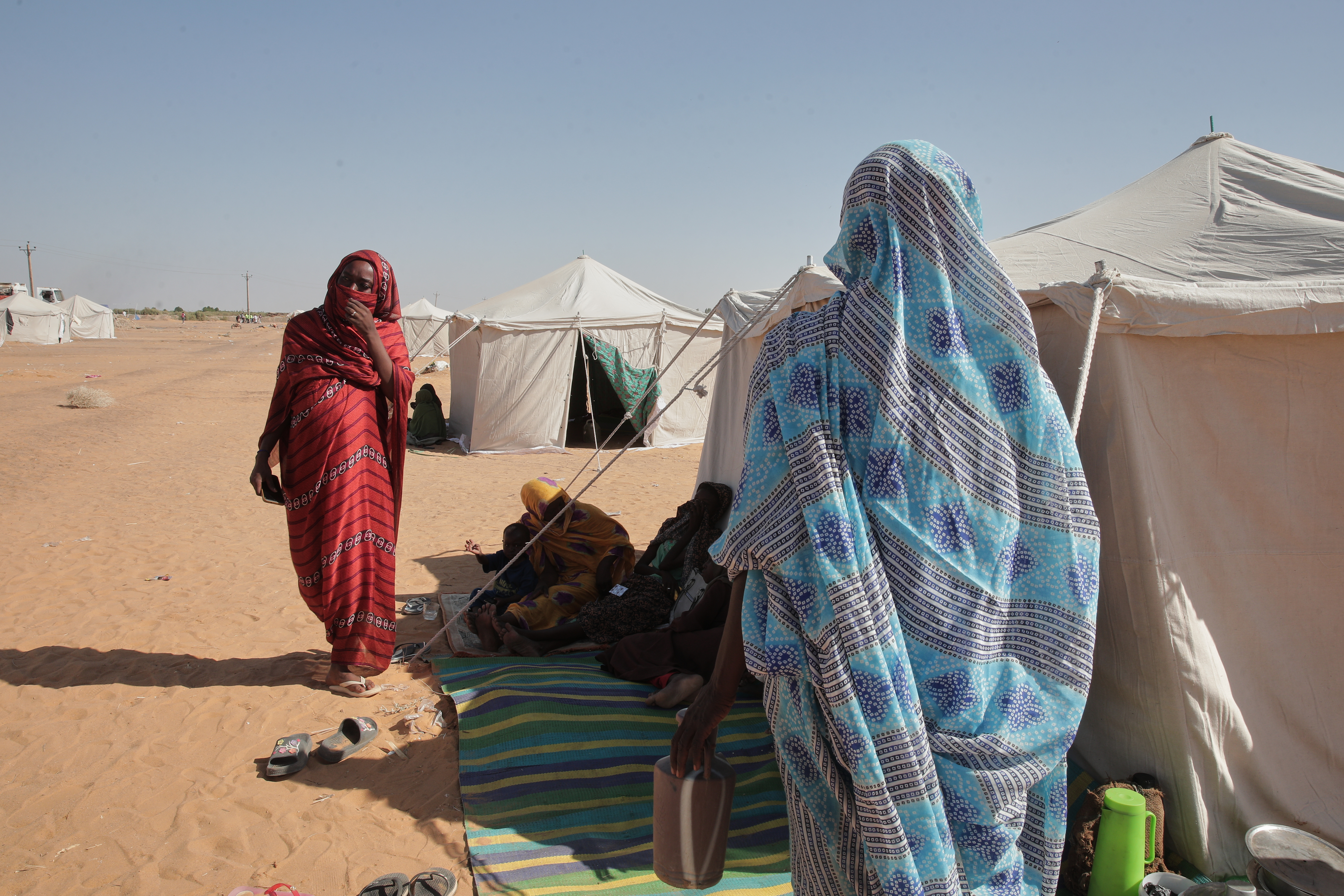 Nadra Mohamed Ahmed, left, stands outside her tent at the newly established El-Afadh camp in Al Dabbah, Sudan's northern state, Monday, Nov. 17, 2025. (AP Photo/Marwan Ali)