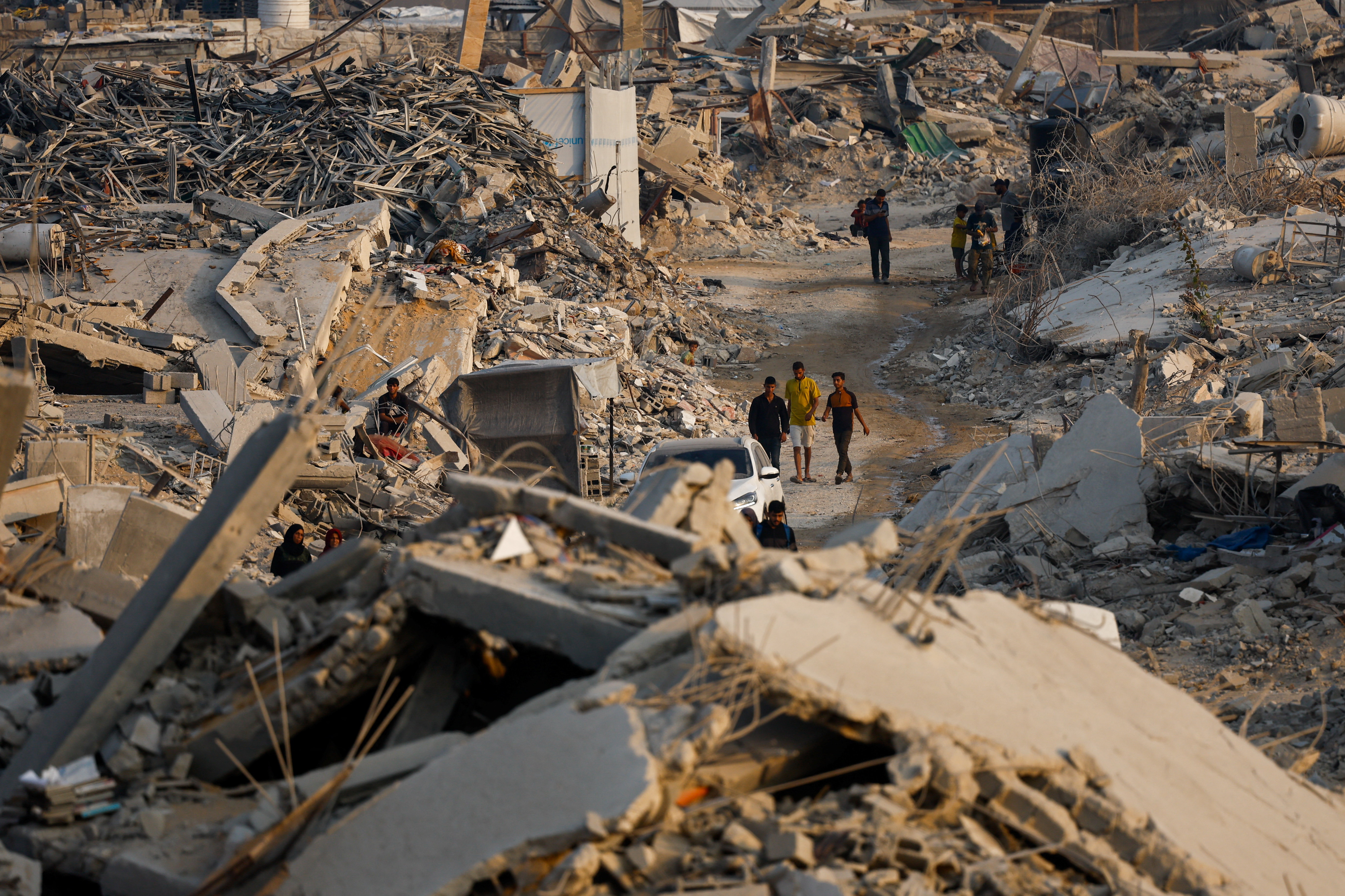 Palestinians walk past the rubble of destroyed buildings, amid a ceasefire between Israel and Hamas, in Jabalia, northern Gaza Strip, November 6, 2025. REUTERS/Mahmoud Issa