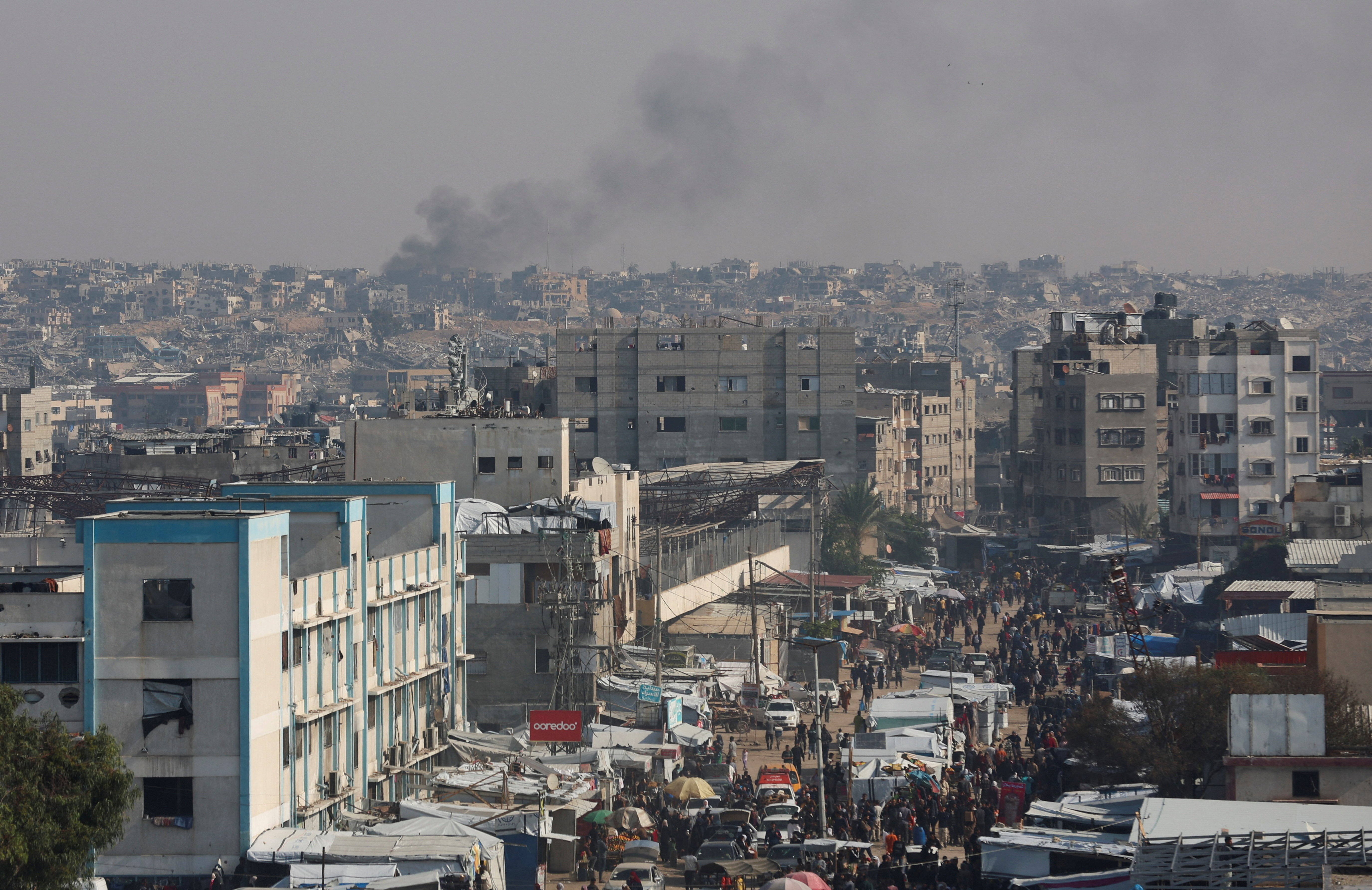 Smoke rises in an area within the so-called "yellow line" to which Israeli troops withdrew under the ceasefire, as displaced Palestinians shelter in tents, in Khan Younis in the southern Gaza Strip