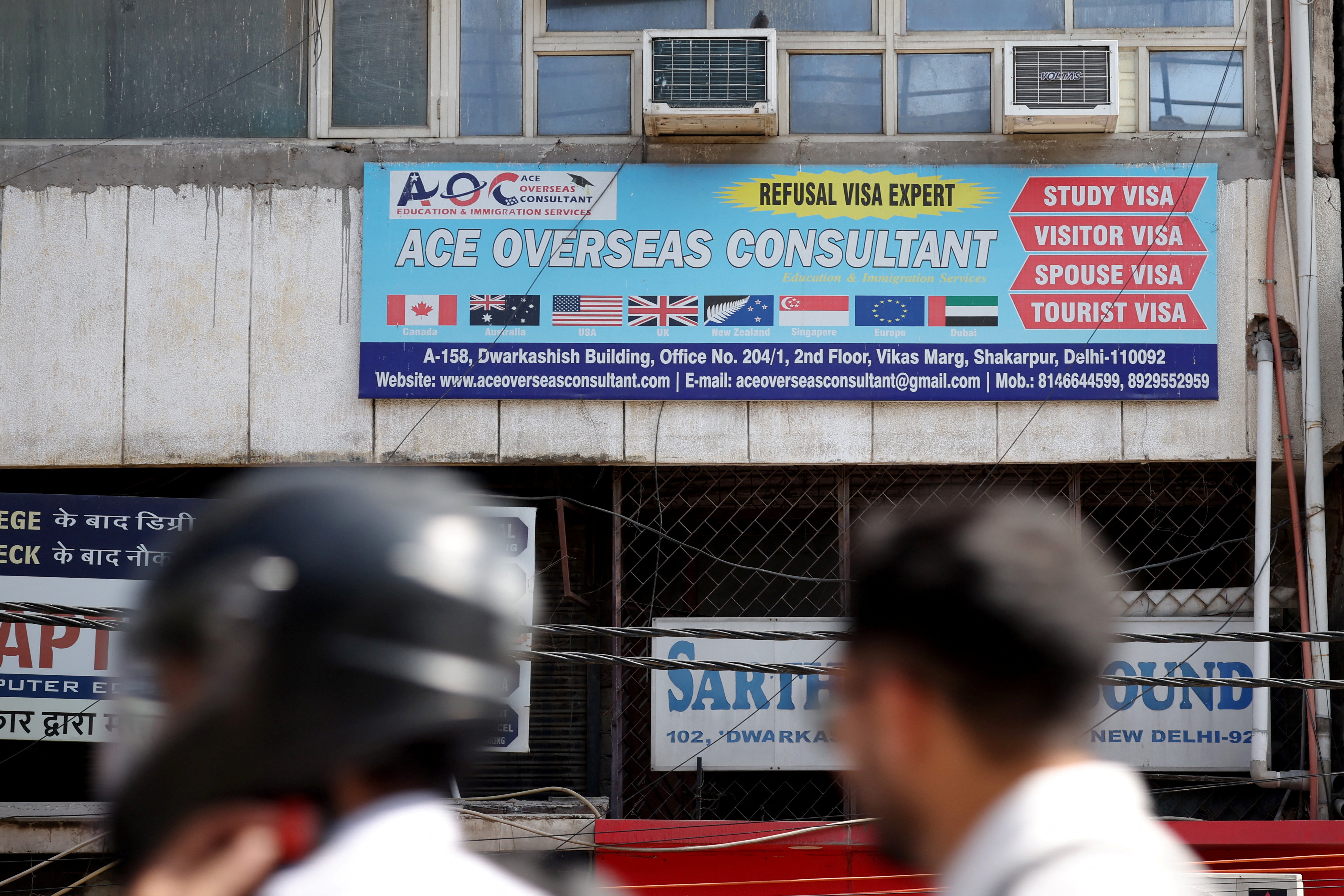 Motorists move past an advertisement of a visa consultancy office in New Delhi, India, September 22, 2025. REUTERS/Adnan Abidi