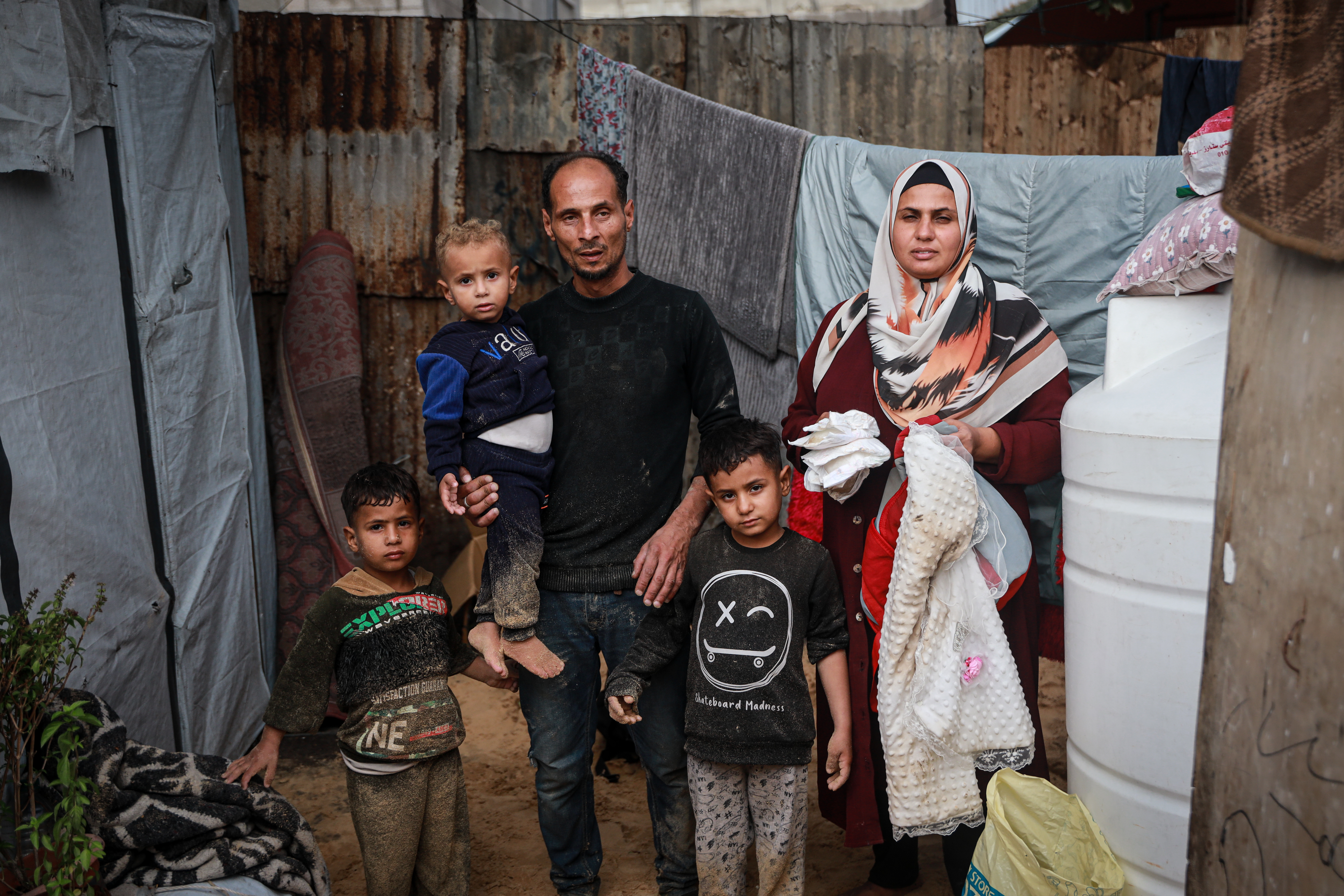 a mother and father and their three young children stand in front of tents