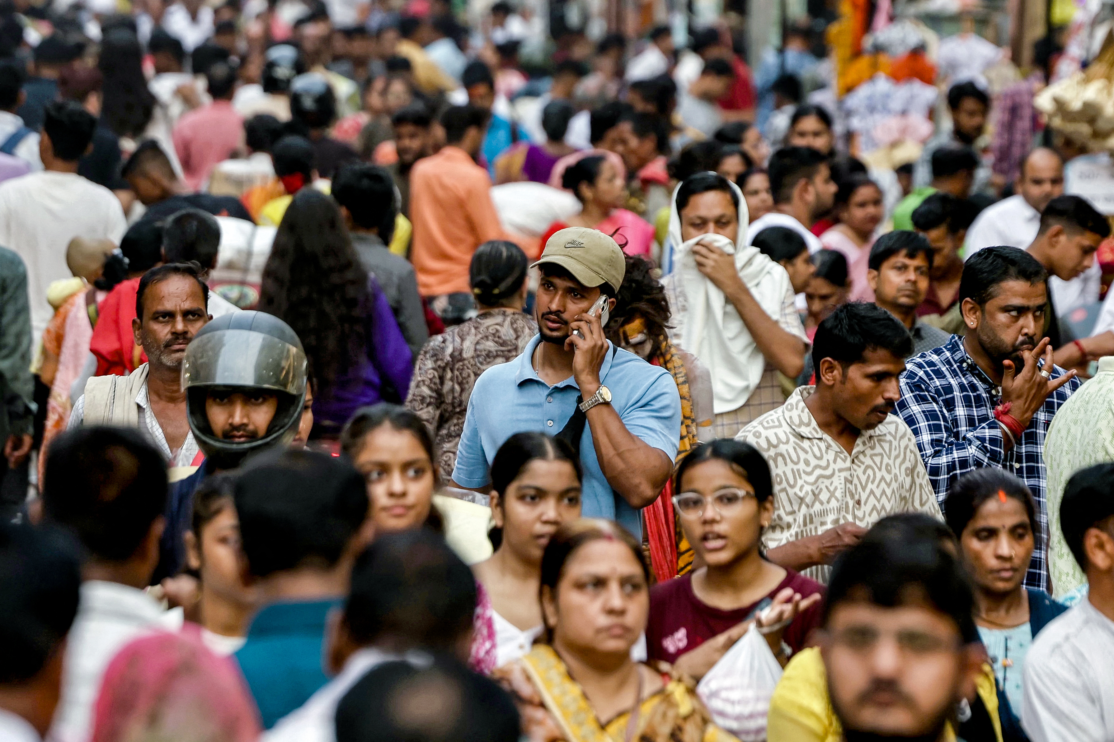 A man speaks on a mobile phone as he walks across a crowded market in Varanasi