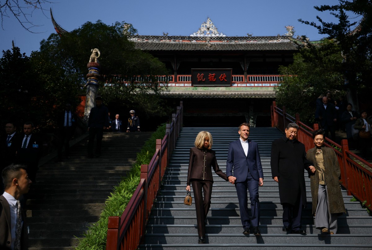 French President Emmanuel Macron (2nd L), his wife Brigitte Macron (L), Chinese President Xi Jinping (2nd R) and his wife Peng Liyuan (R) visit the Dujiangyan site, a designated UNESCO World Heritage site, in Dujiangyan, in southwestern China's Sichuan province on December 5, 2025. (Photo by Sarah Meyssonnier / POOL / AFP)