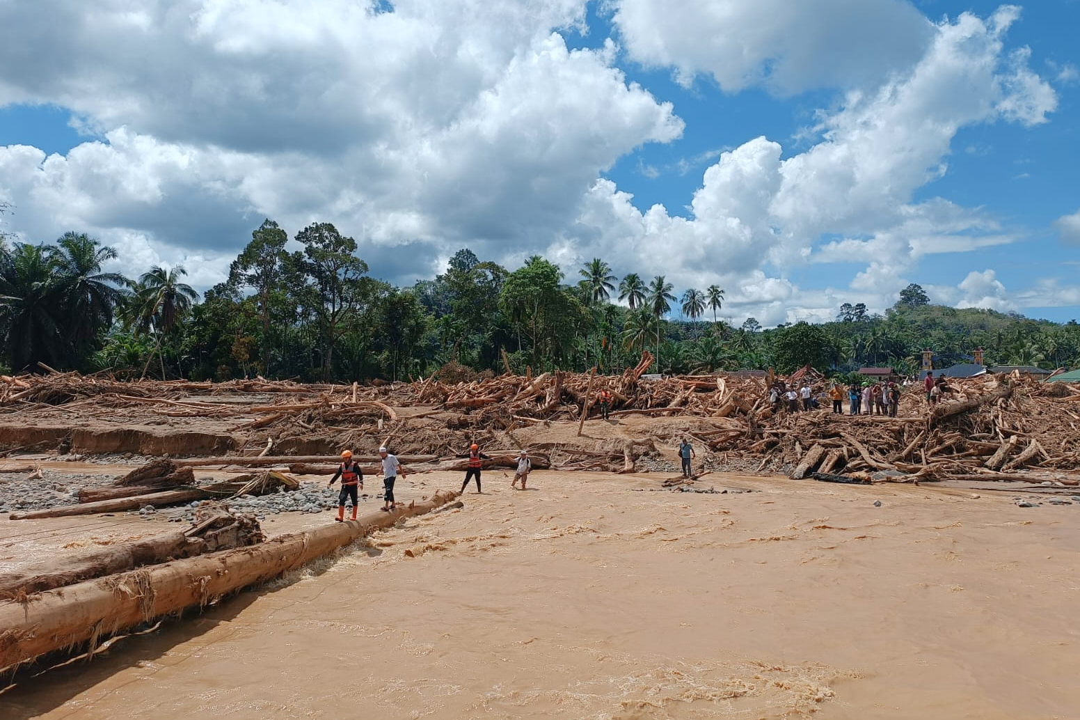 Rescuers walk on a log to cross a river during the search for flood victims in Batang Toru, North Sumatra, Indonesia, Monday, Dec. 1, 2025. (AP Photo/Binsar Bakkara)