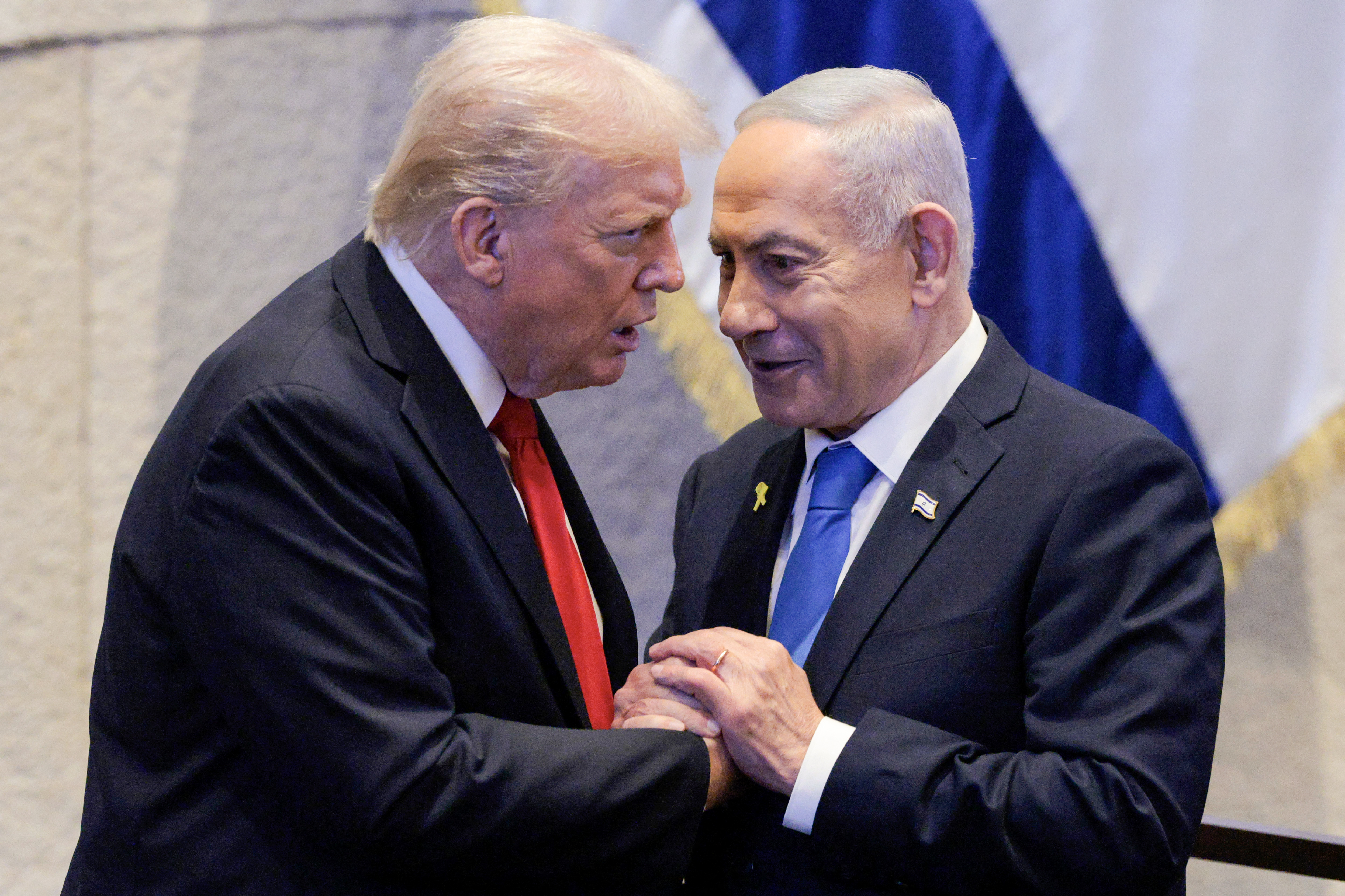 (FILES) US President Donald Trump (L) holds hands and speaks with Israeli Prime Minister Benjamin Netanyahu at the Israeli parliament, the Knesset, in Jerusalem on October 13, 2025.