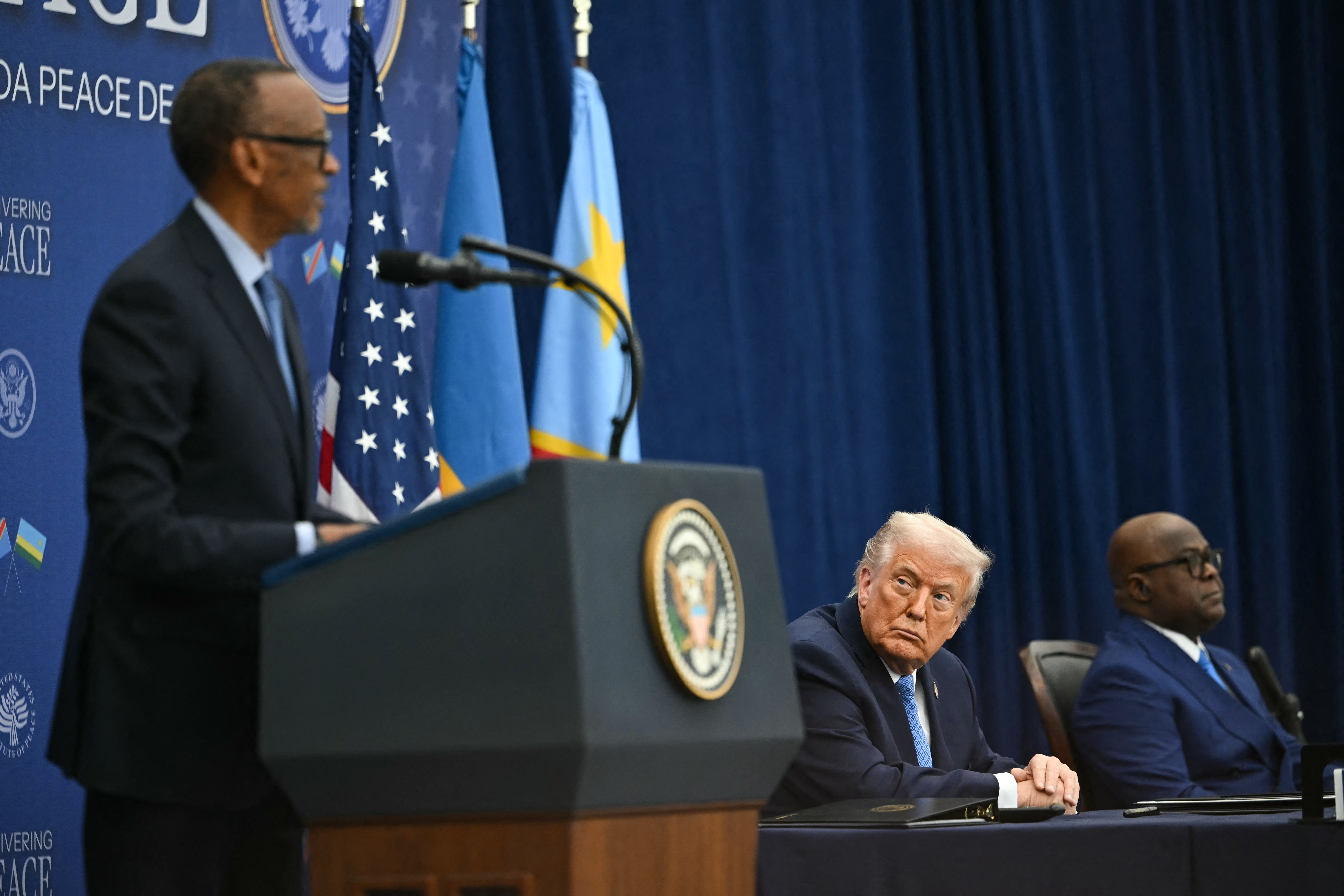 US President Donald Trump (C) and President of the Democratic Republic of the Congo Felix Tshisekedi (R) look on as President of Rwanda Paul Kagame (L) speaks during a signing ceremony of a peace deal at the United States Institute of Peace in Washington, DC, on December 4, 2025.