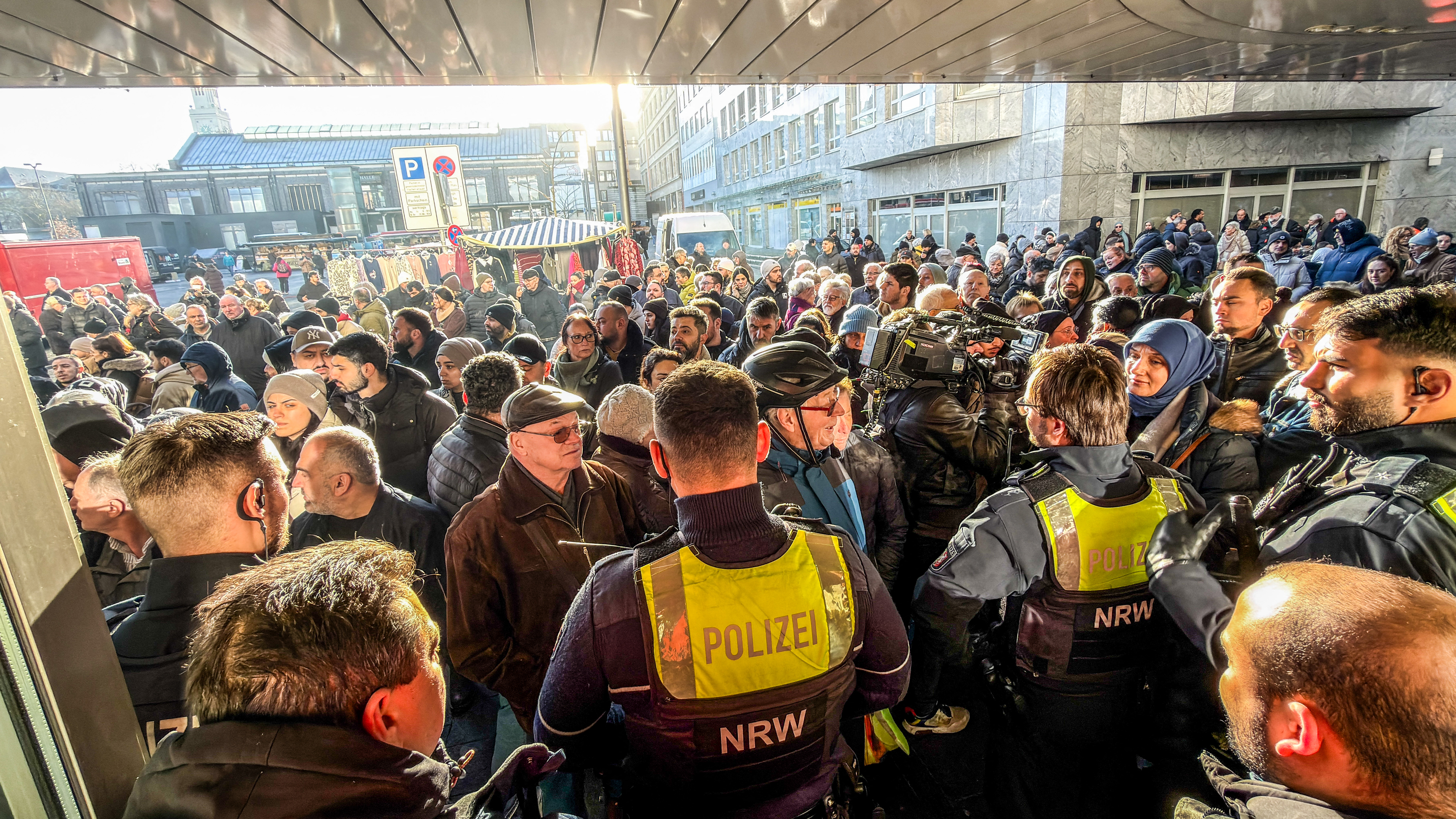 Policemen and bank customers stand in front of a branch of the Sparkasse bank.