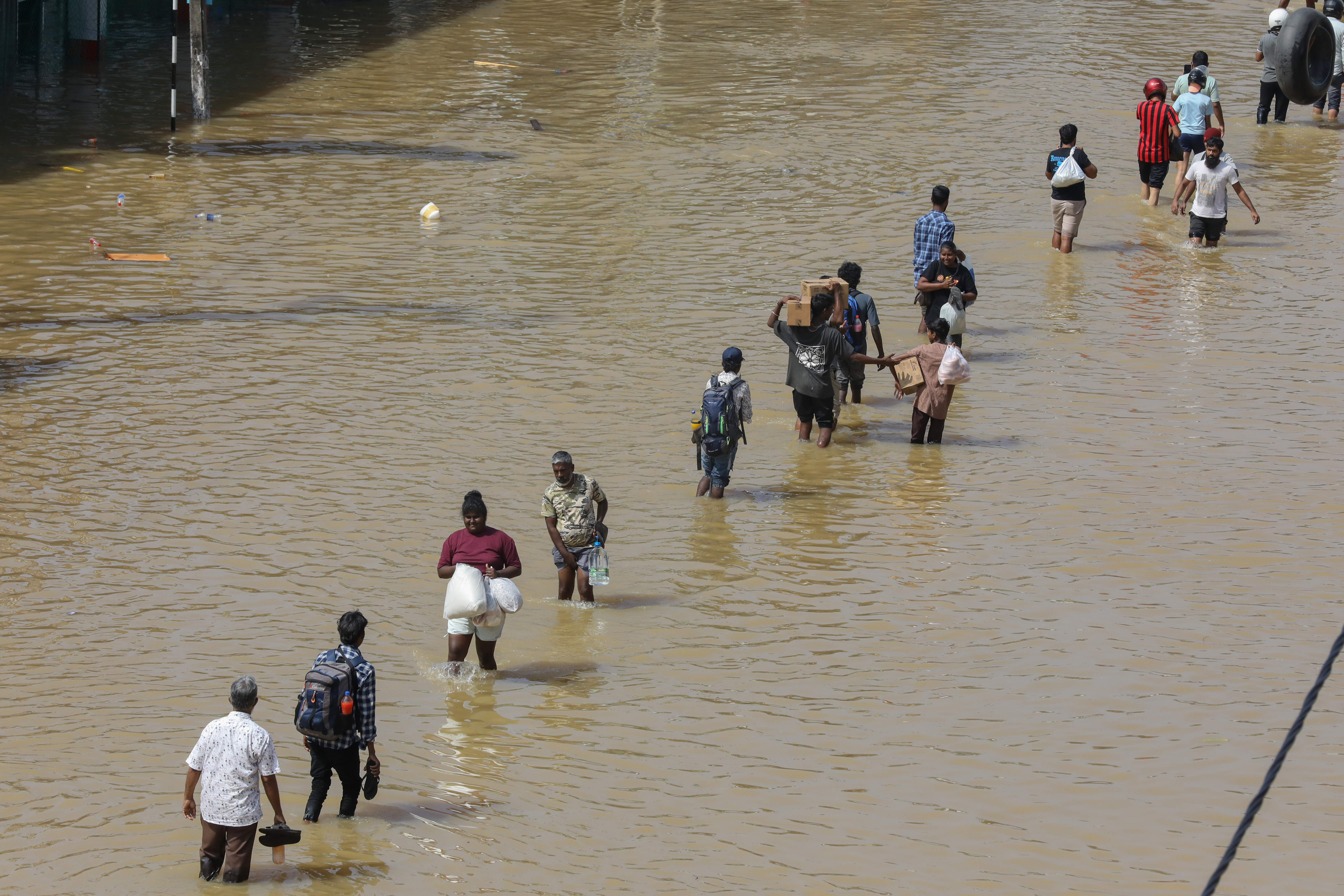 epa12559522 People wade through a flooded road after heavy rainfall in a suburb of Colombo, Sri Lanka, 30 November 2025. Many parts of the island have been inundated due to heavy rains. According to the Sri Lanka Disaster Management Center, more than 160 people have been killed and about 200 are missing around the country. EPA/CHAMILA KARUNARATHNE