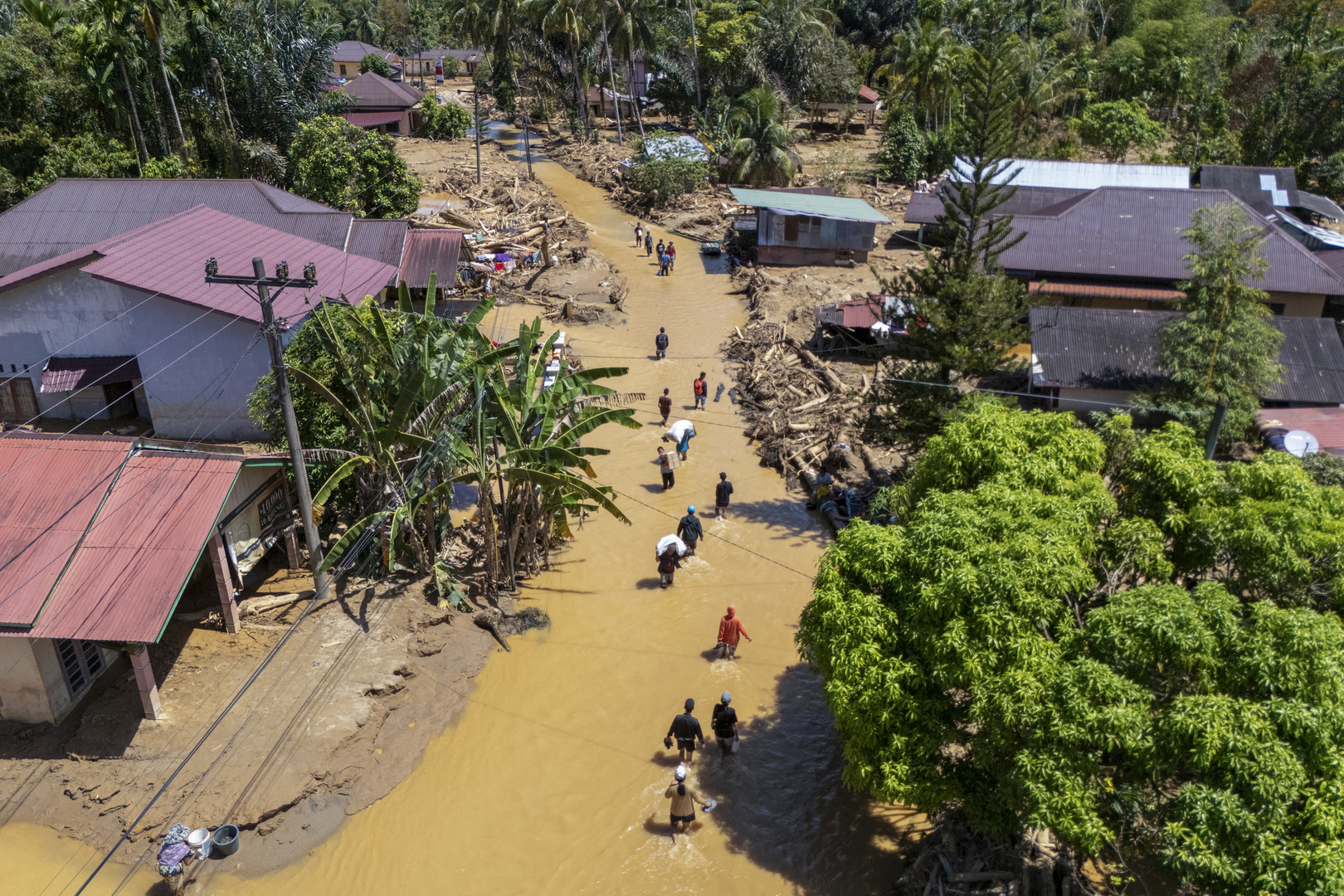 This picture shows an aerial view of villagers wading through the mudflow to find a shelter in the aftermath of flash floods in Tukka village, Central Tapanuli, North Sumatra province on Dec. 3, 2025. [Y.T Haryono/AFP]