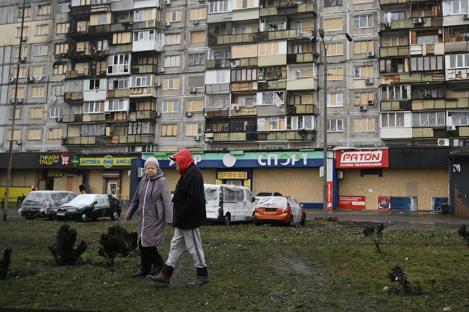People walk in front of a residential building damaged after a recent air attack, in Kyiv on Dec. 3, 2025, amid the Russian invasion of Ukraine. [Genya Savilov/AFP]