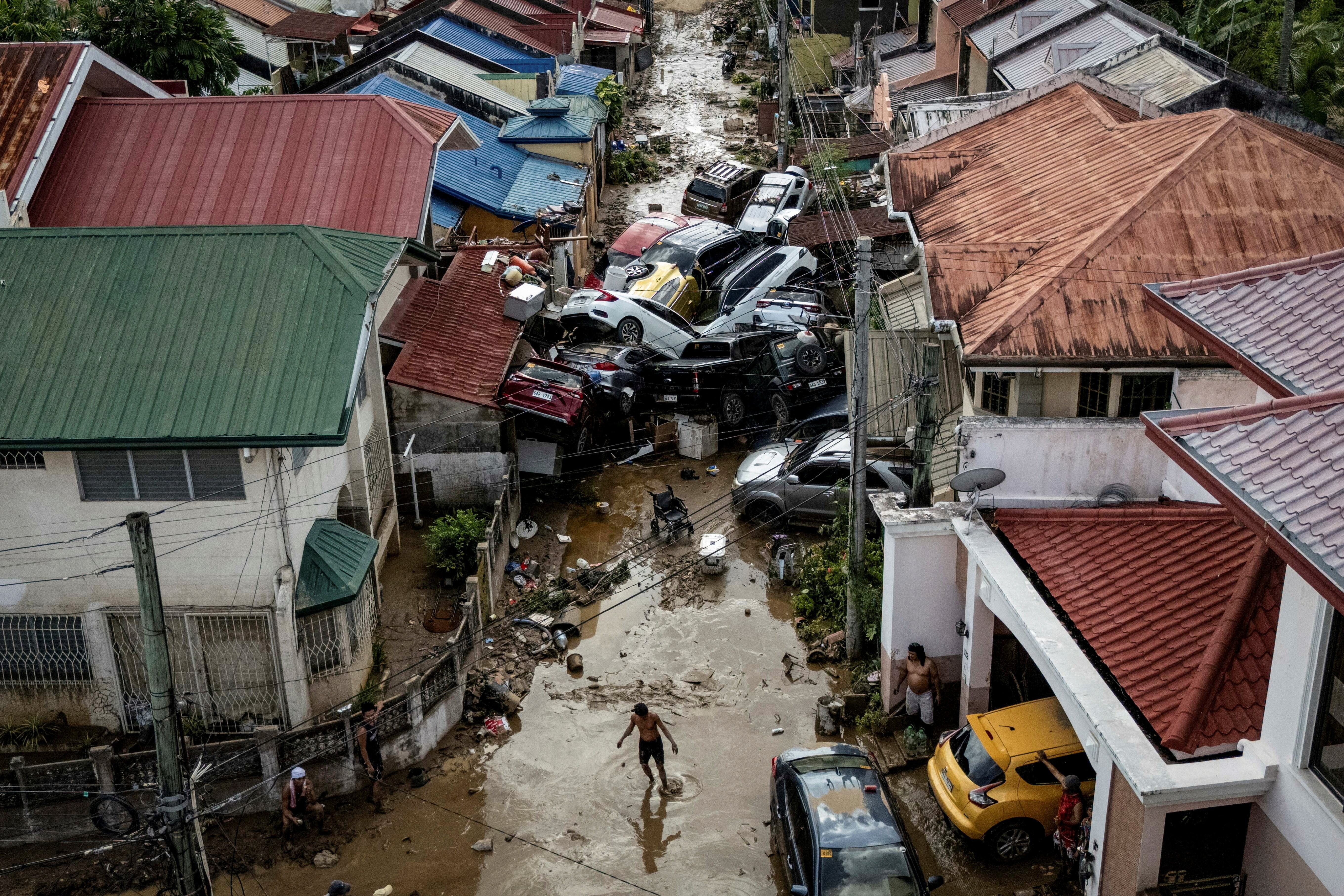 A drone view shows a man crossing a muddy street where cars piled up after being swept away in floods brought on by Typhoon Kalmaegi which piled up at a subdivision in Bacayan, Cebu City, Philippines, November 5, 2025. REUTERS/Eloisa Lopez TPX IMAGES OF THE DAY SEARCH "REUTERS BEST 2025" FOR THIS STORY. SEARCH "REUTERS 2025 YEAR-END" FOR ALL 2025 YEAR END GALLERIES.
