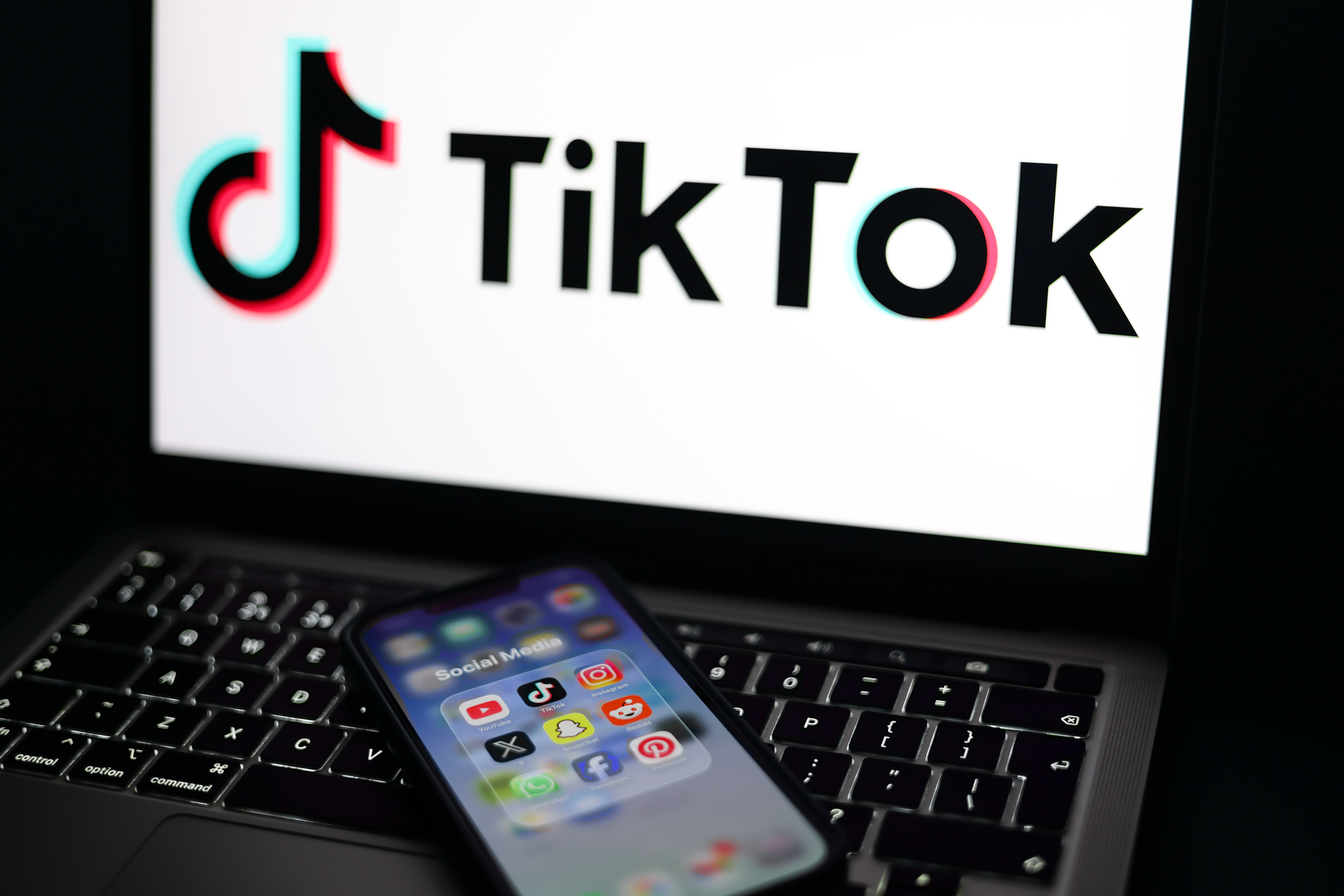 epa12674787 Social media applications displayed on a mobile phone alongside the TikTok logo displayed on a laptop screen in Liverpool, Britain, 23 January 2026. A proposal to ban under-16s from accessing social media in the UK will be considered in the House of Commons after peers in the House of Lords voted 261 to 150 in favour of an amendment to the Children’s Wellbeing and Schools Bill. If adopted, the amendment would require social media companies to implement strict and effective age checks in order to prevent underage users from signing up. EPA/ADAM VAUGHAN