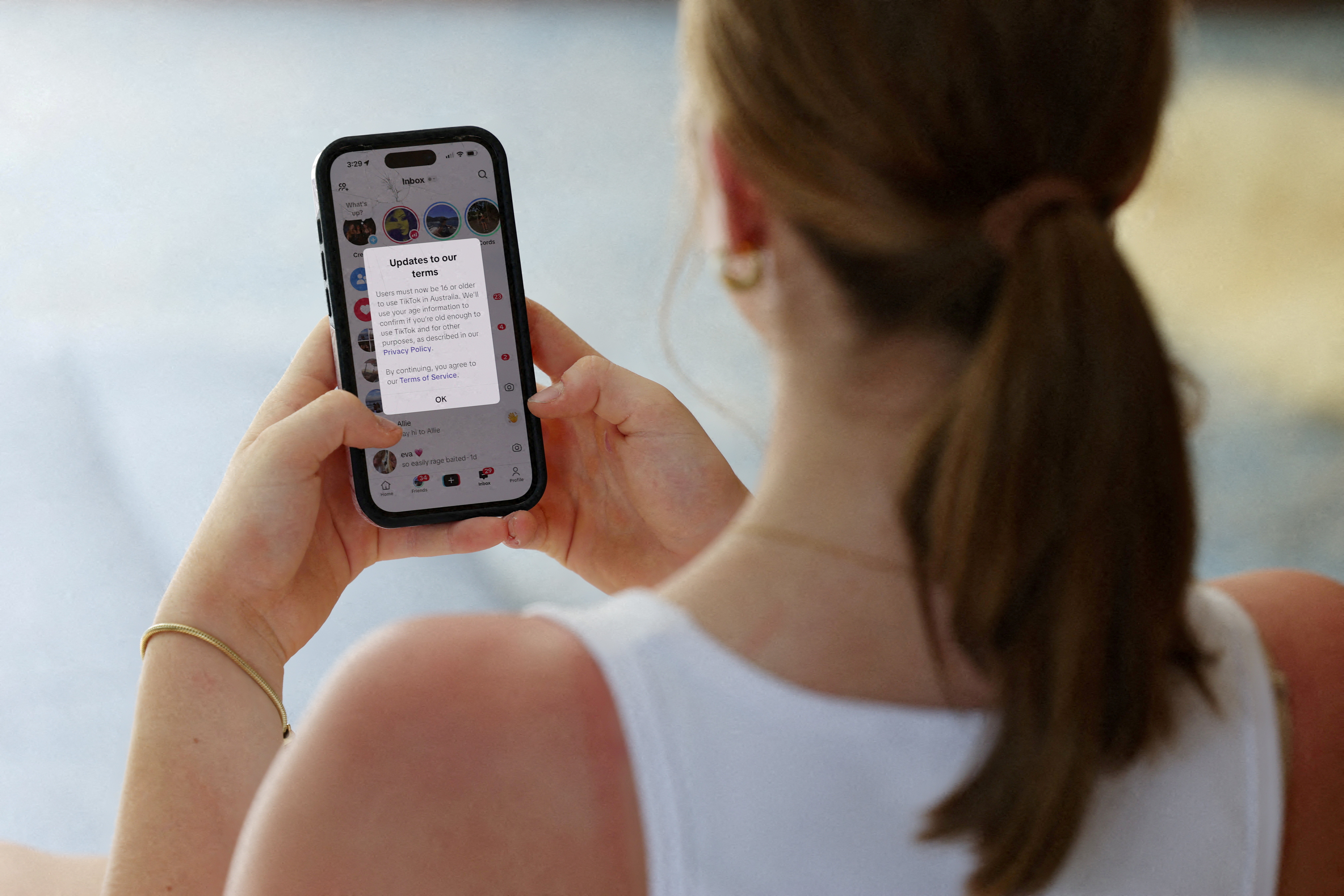 FILE PHOTO: A teenager poses holding a mobile phone displaying a message from TikTok as law banning social media for users under 16 in Australia takes effect, in Sydney, Australia, December 10, 2025. REUTERS/Hollie Adams/File Photo