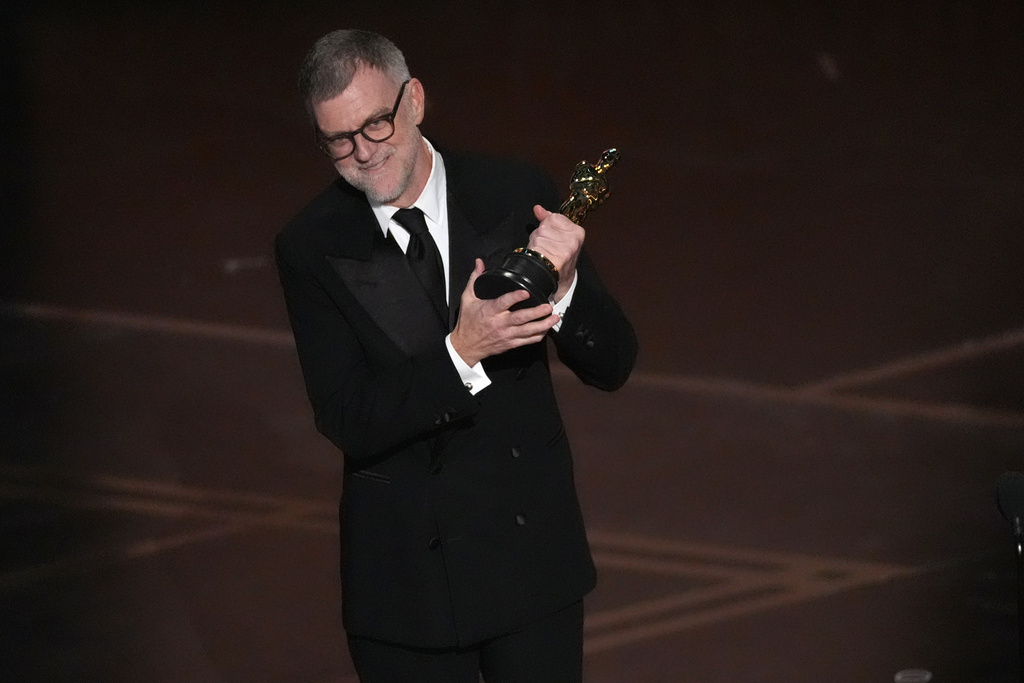 Paul Thomas Anderson holds an Oscar on stage