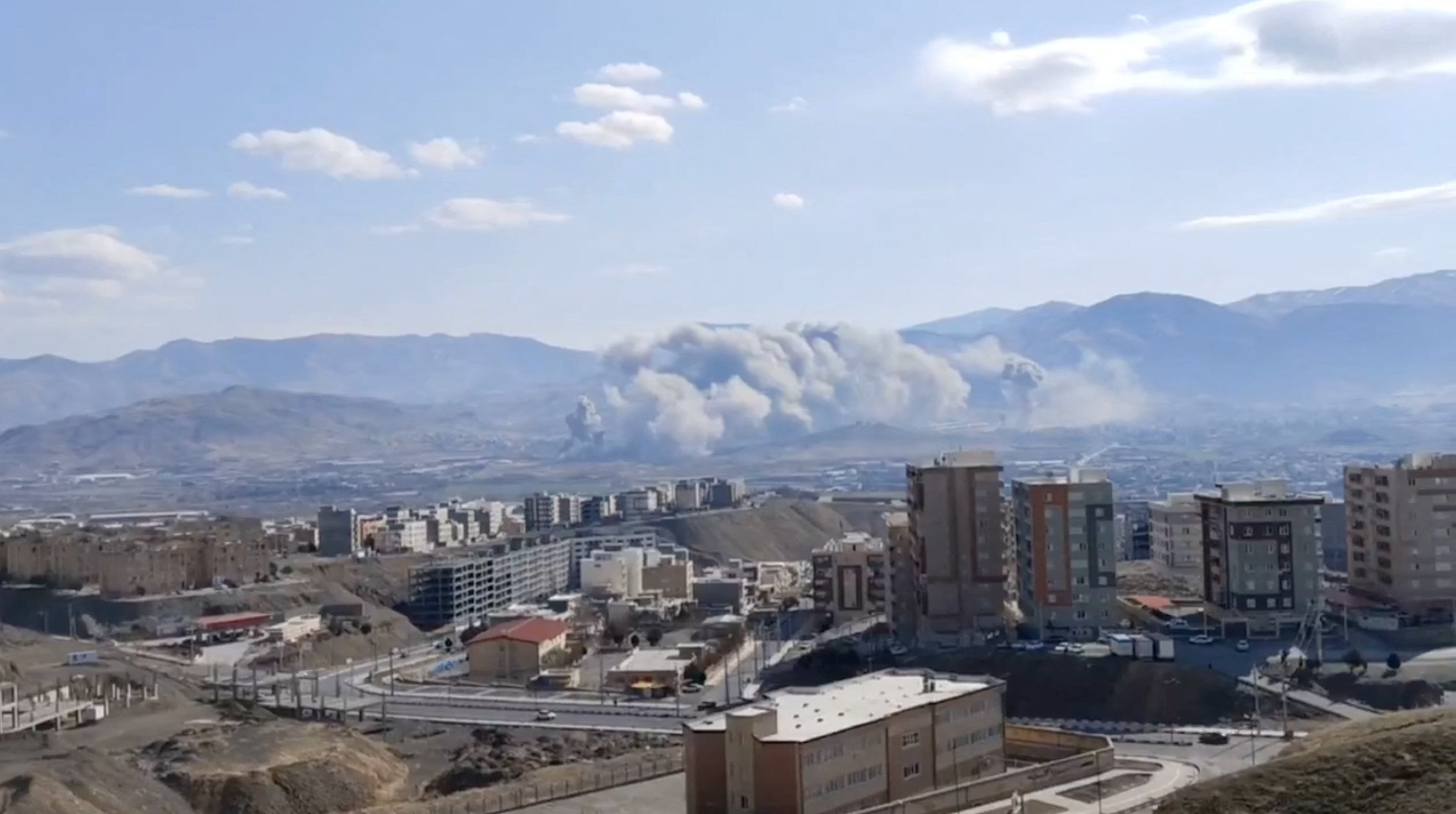 Smoke plumes rise from a city.