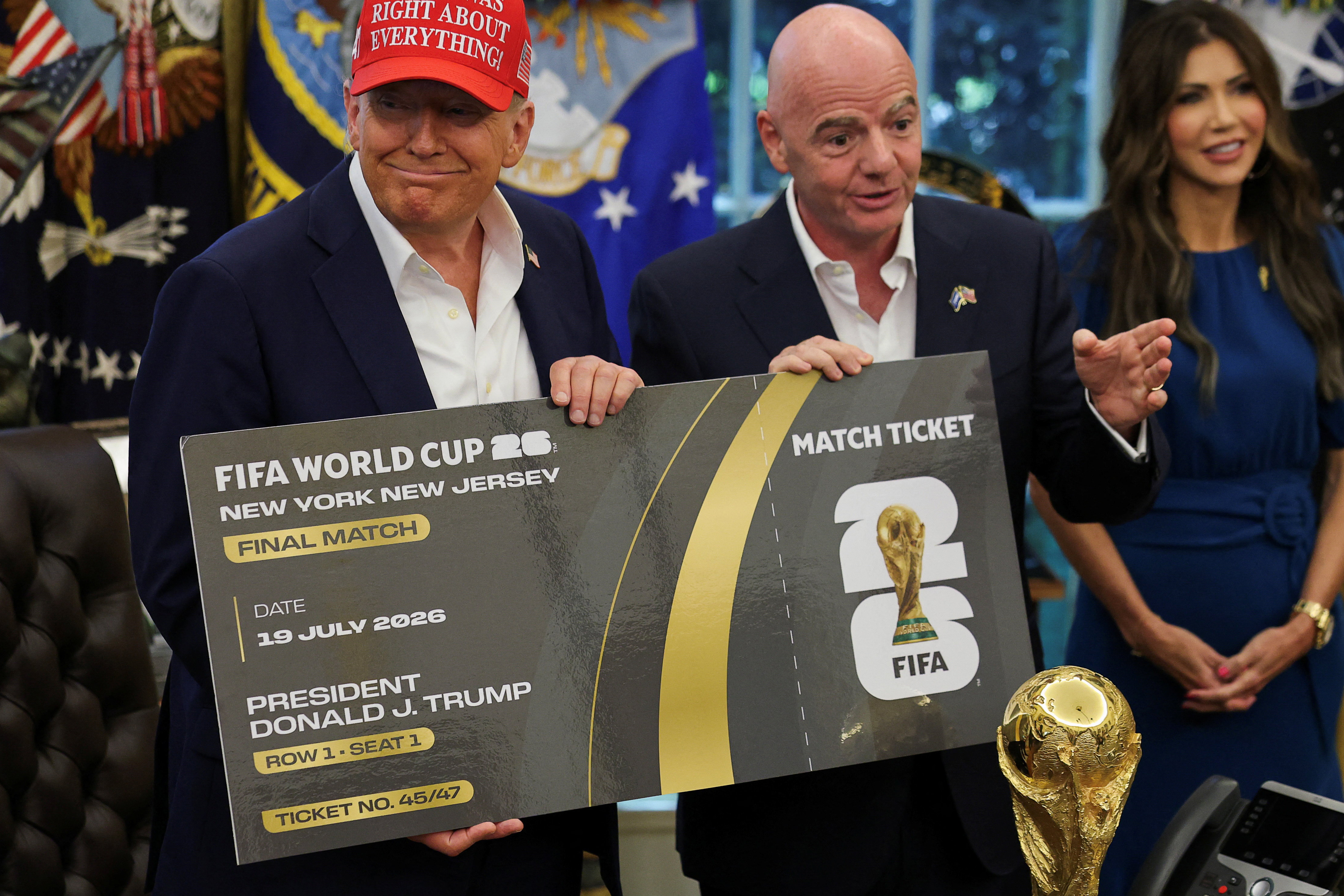 U.S. President Donald Trump and FIFA president Gianni Infantino hold a 2026 FIFA World Cup final match ticket that was presented to President Trump, as the President makes an announcement on the 2026 FIFA World Cup, while U.S. Homeland Security Secretary Kristi Noem stands, in the Oval Office at the White House in Washington, D.C., U.S., August 22, 2025. REUTERS/Jonathan Ernst