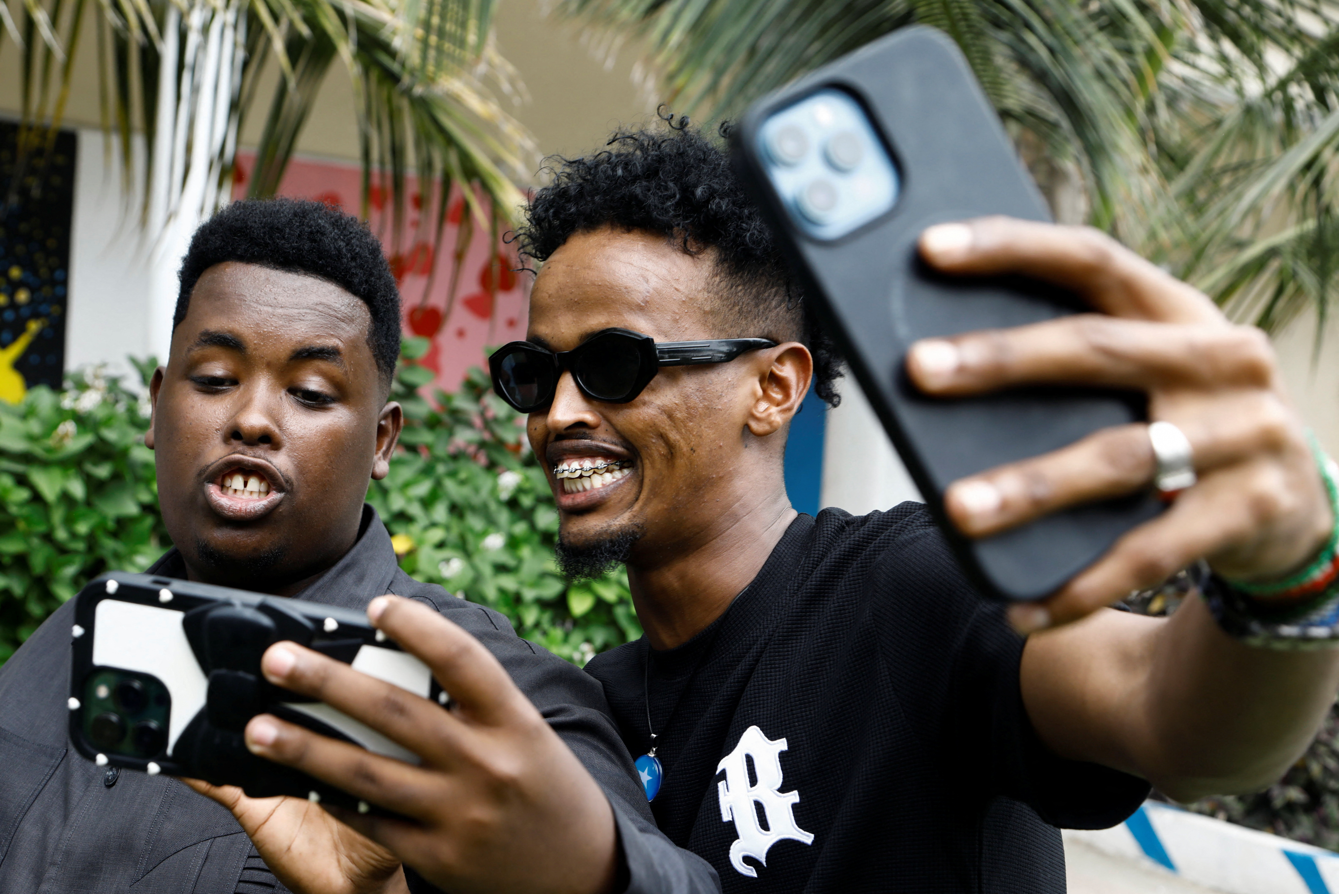 Two young men look at a mobile phone screen.