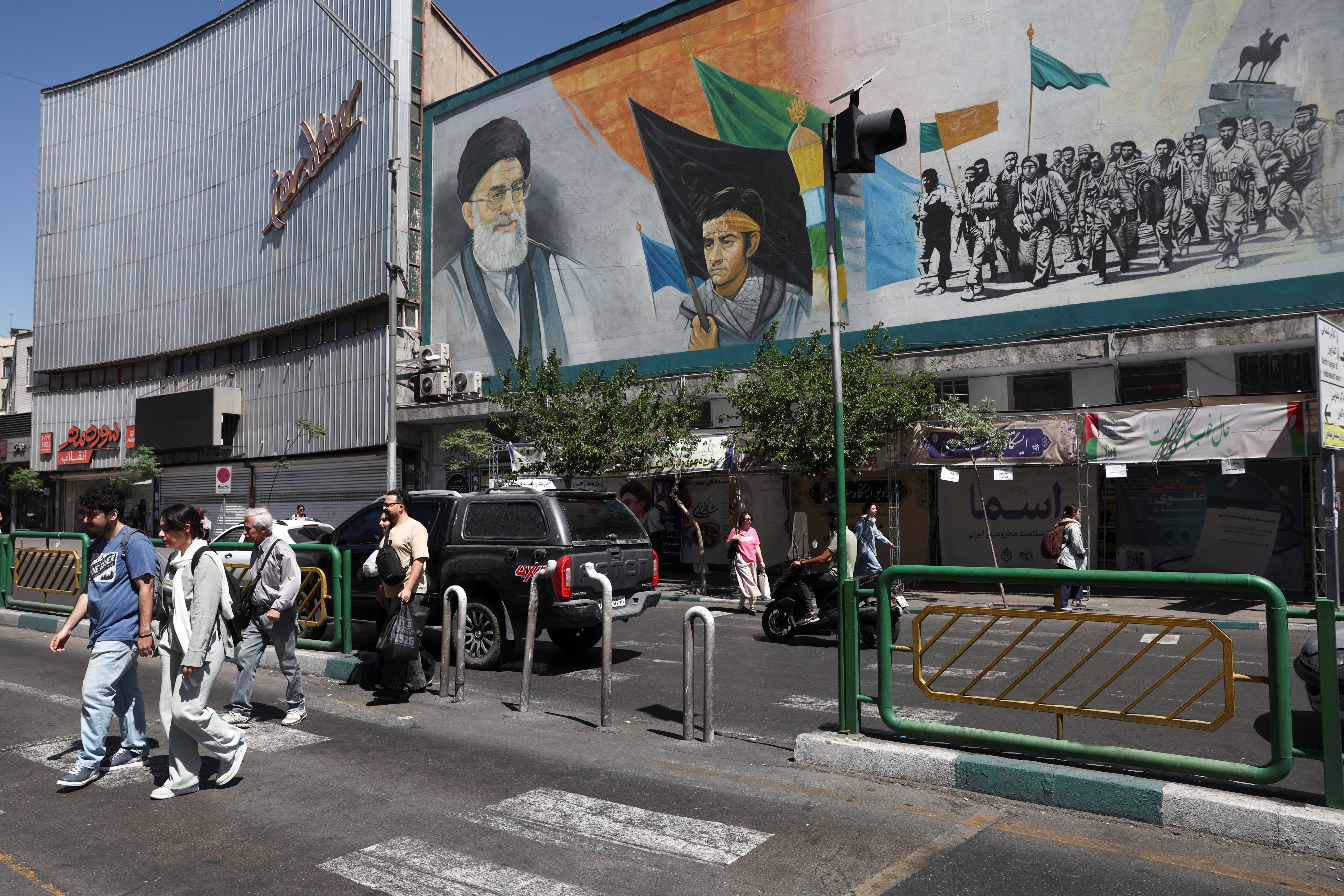 People walk past a mural depicting Iran's late Supreme Leader Ayatollah Ali Khamenei.