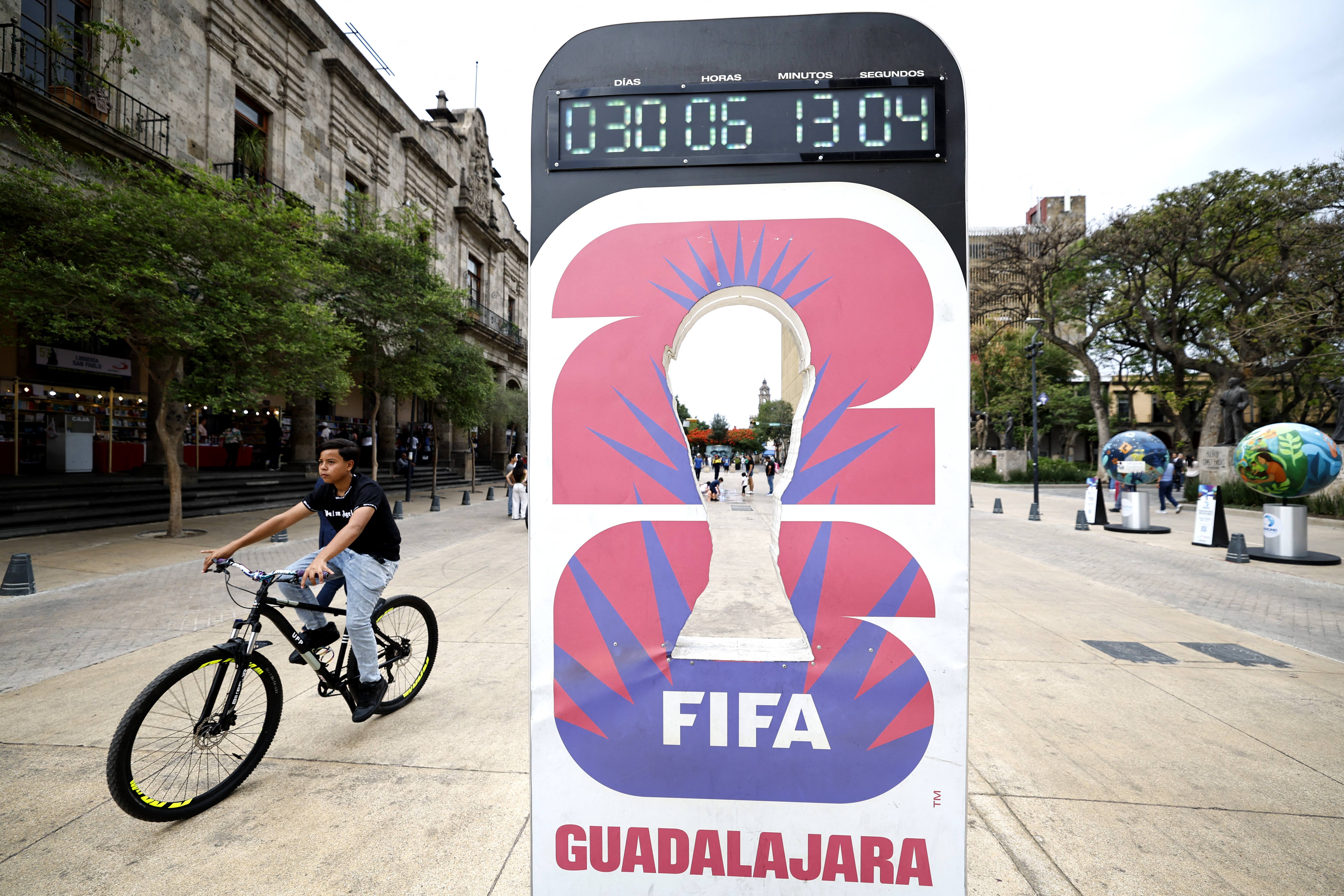A man rides past a clock marking 30 days to the 2026 FIFA World Cup.