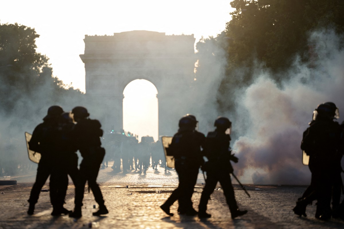 French Republican Security Corps (CRS - Compagnies Republicaines de Securite) Police officers walk amid smoke from teargas on the Champs-Elysees Avenue
