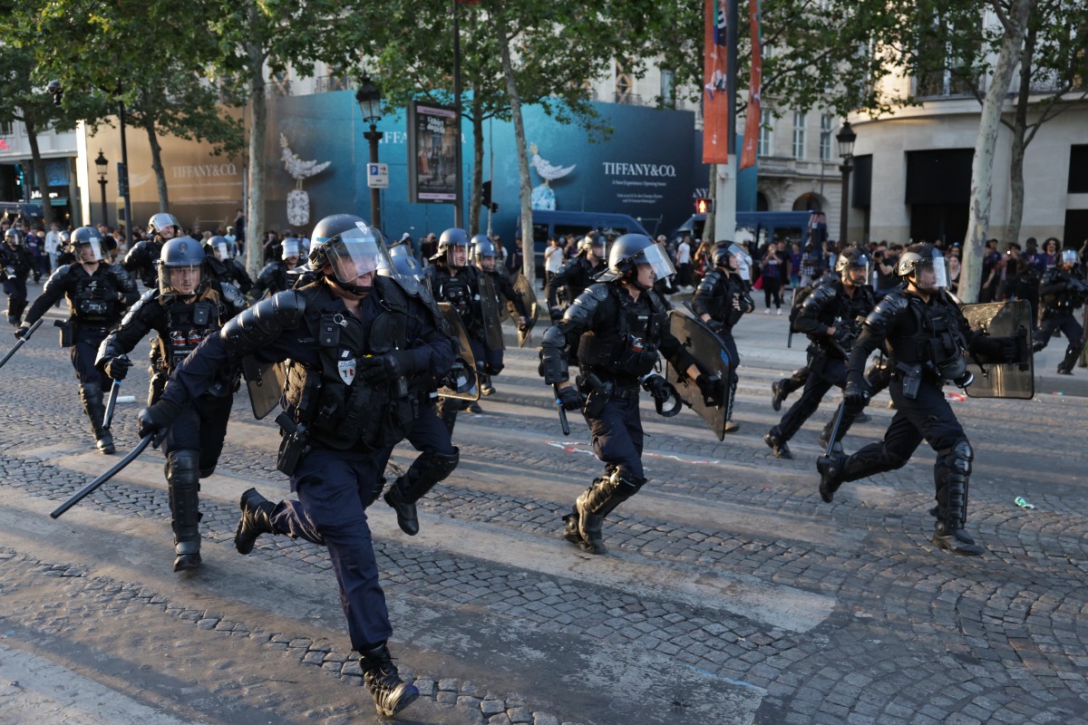 French Republican Security Corps (CRS - Compagnies Republicaines de Securite) Police officers walk amid smoke from teargas on the Champs-Elysees Avenue